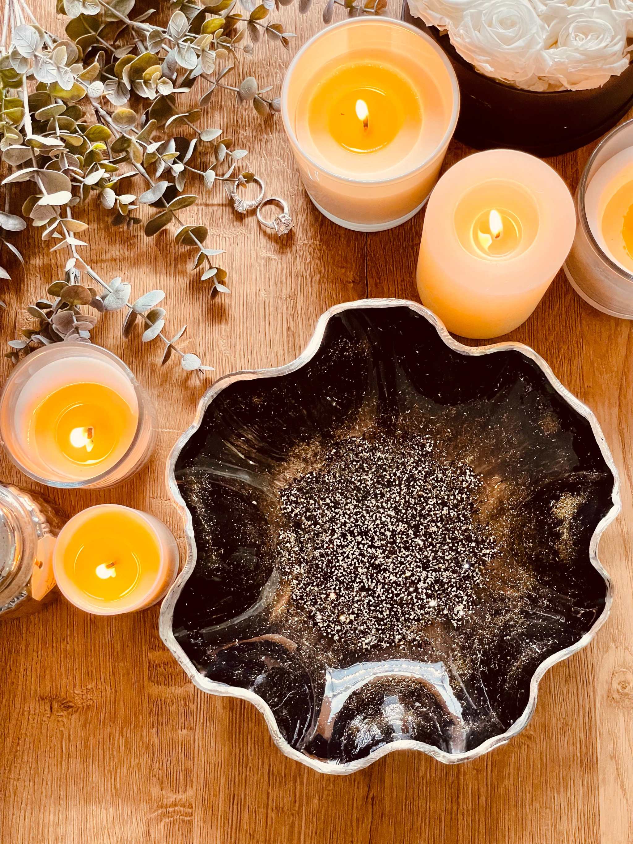 Handgemachte schwarze Schale aus Resin mit silbernen Details und unregelmäßigem Rand auf Holztisch mit brennenden Kerzen