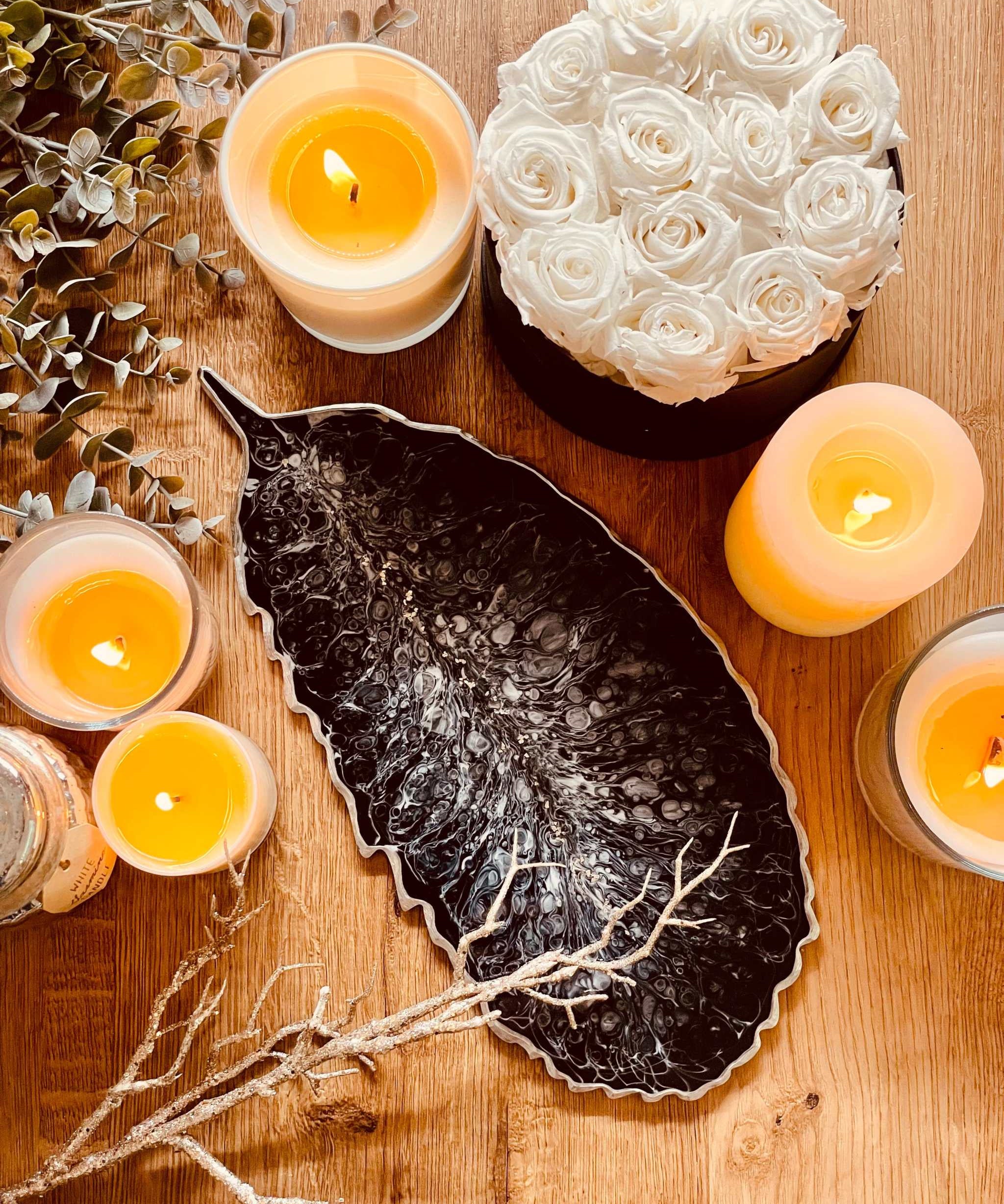 Schwarzes handgemachtes Feder Tablett aus Resin mit silbernen Details als dekoratives Unikat auf Holztisch mit Kerzen und weißen Rosen