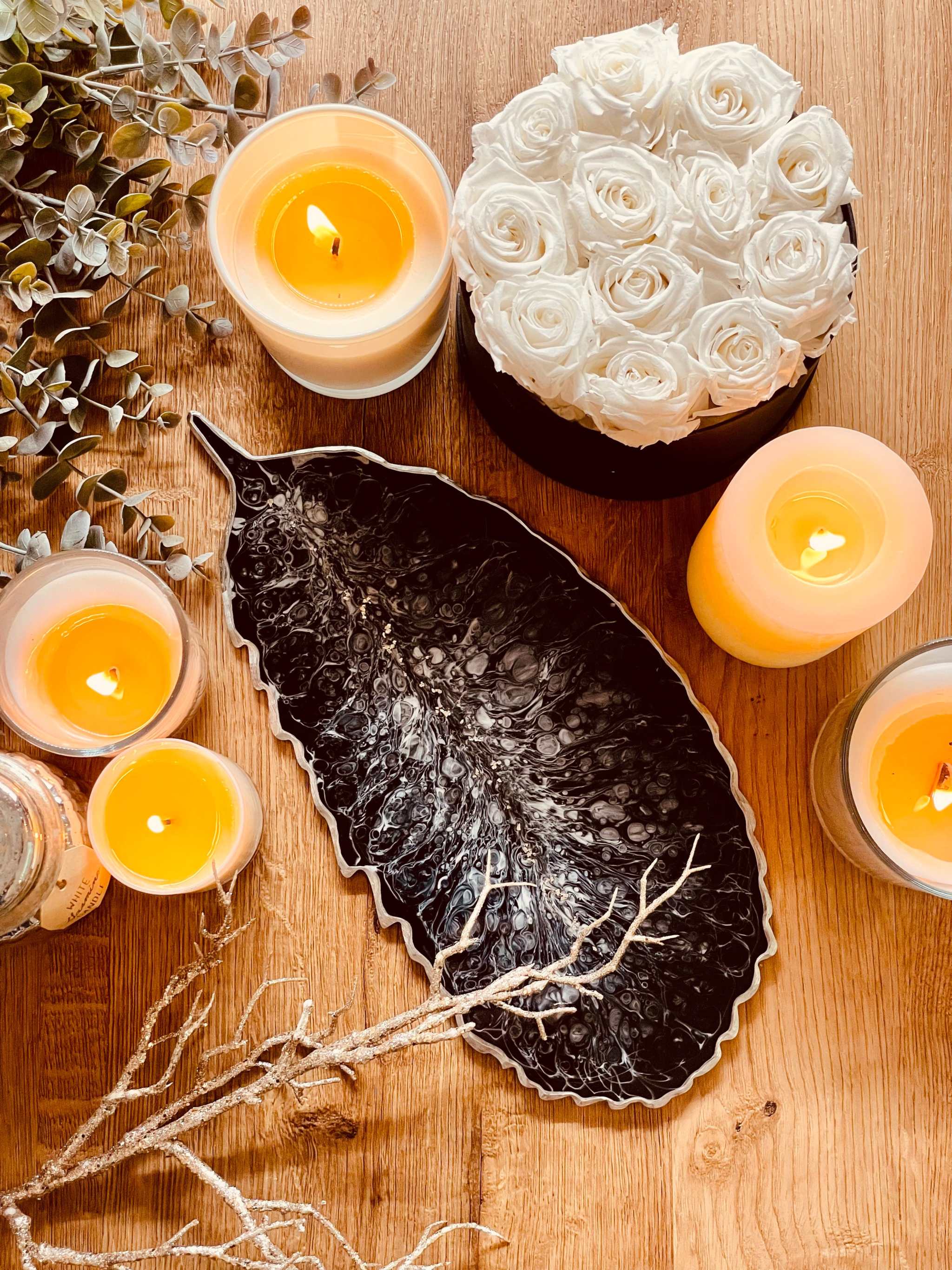 Schwarzes handgemachtes Feder Tablett aus Resin mit silbernen Details als dekoratives Unikat auf Holztisch mit Kerzen und weißen Rosen