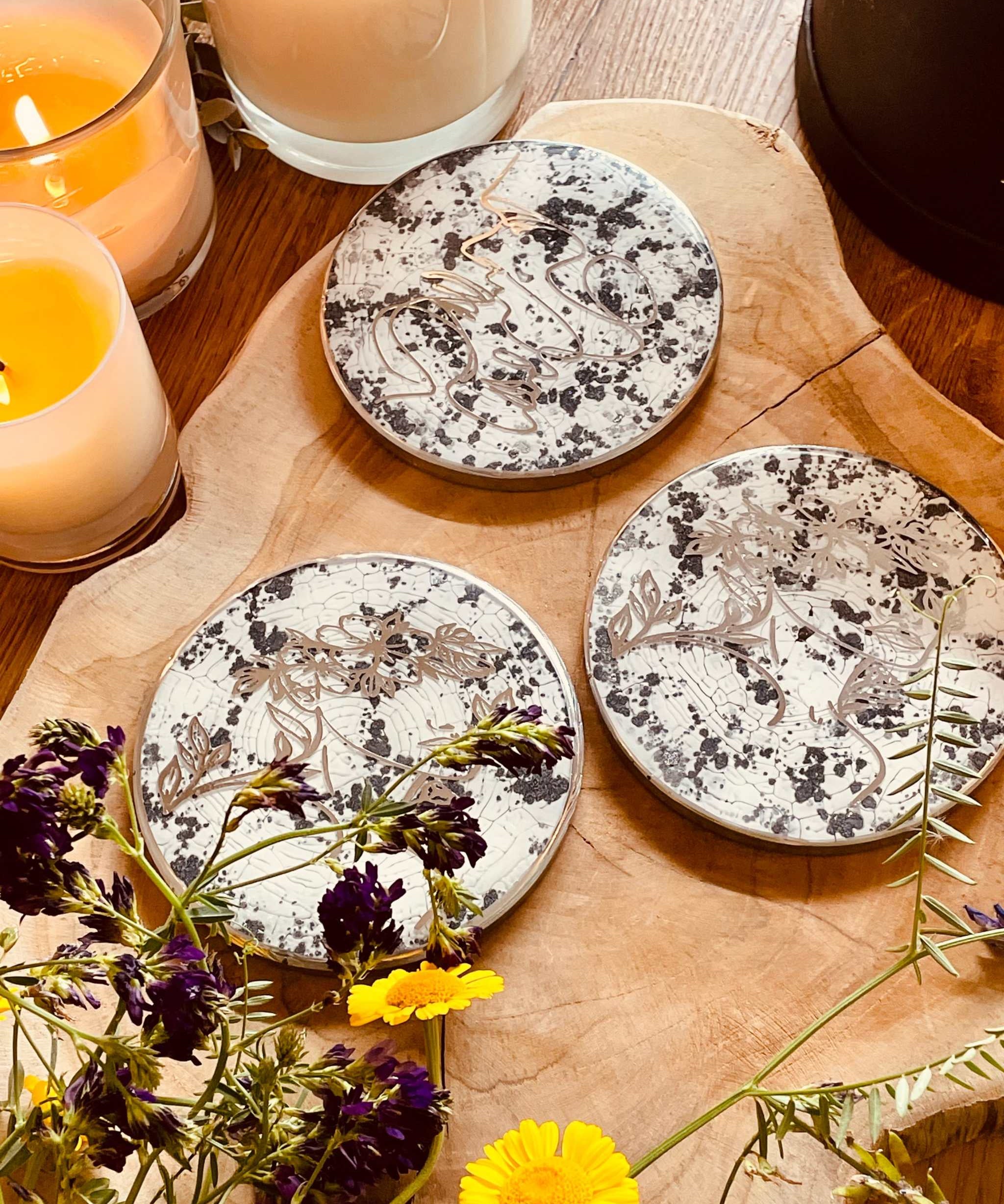 3 Untersetzer aus Resin in Schwarz Weiss Silber mit LineArt handgemacht als einzigartiges 3-teiliges Set auf Holztisch mit Kerzen und Blumen dekoriert