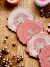 4 Untersetzer aus handgemachtem rosa Resin mit silbernen Details auf Holztisch