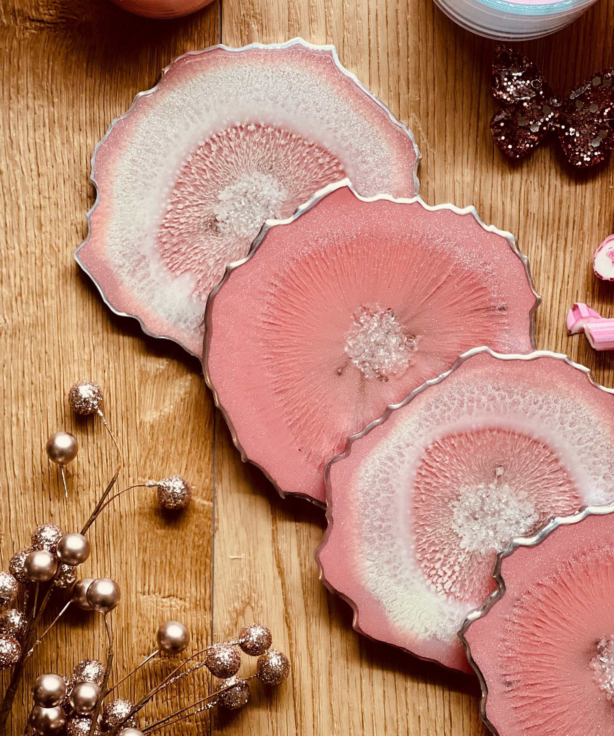4 Untersetzer aus handgemachtem rosa Resin mit silbernen Details auf Holztisch
