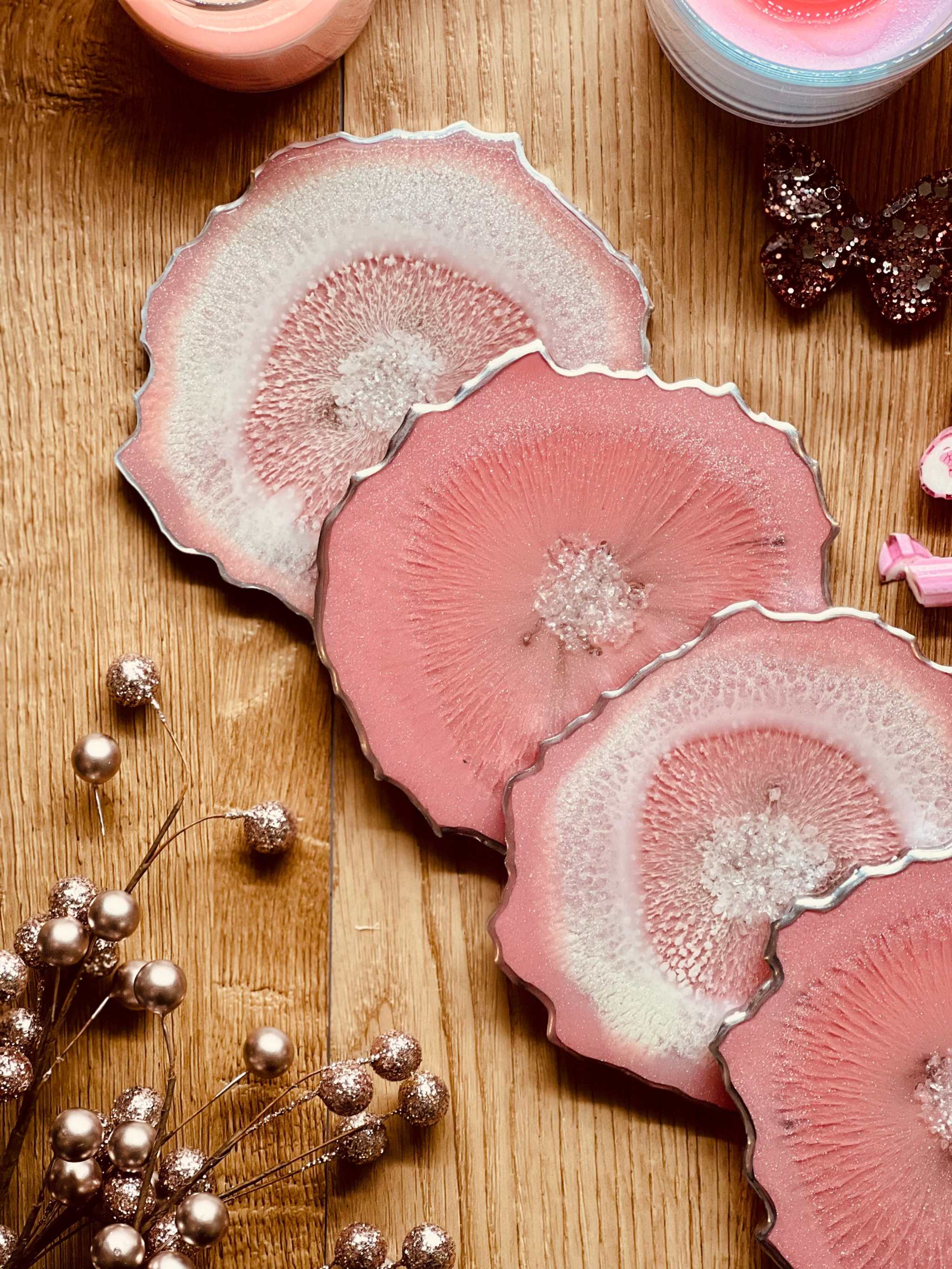 4 Untersetzer aus handgemachtem rosa Resin mit silbernen Details auf Holztisch