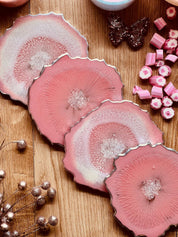 4 Untersetzer aus handgemachtem rosa Resin mit silbernen Details und ca. 12cm Durchmesser auf Holztisch
