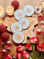 Handgemachte weiße Untersetzer aus Resin mit goldenen Details auf Holztisch mit Kerzen und Rosen