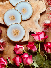 Set aus 5 handgemachten Untersetzern aus weißem Resin mit goldenen Details auf Holzplatte, dekoriert mit rosa Rosen und Weihnachtskugeln