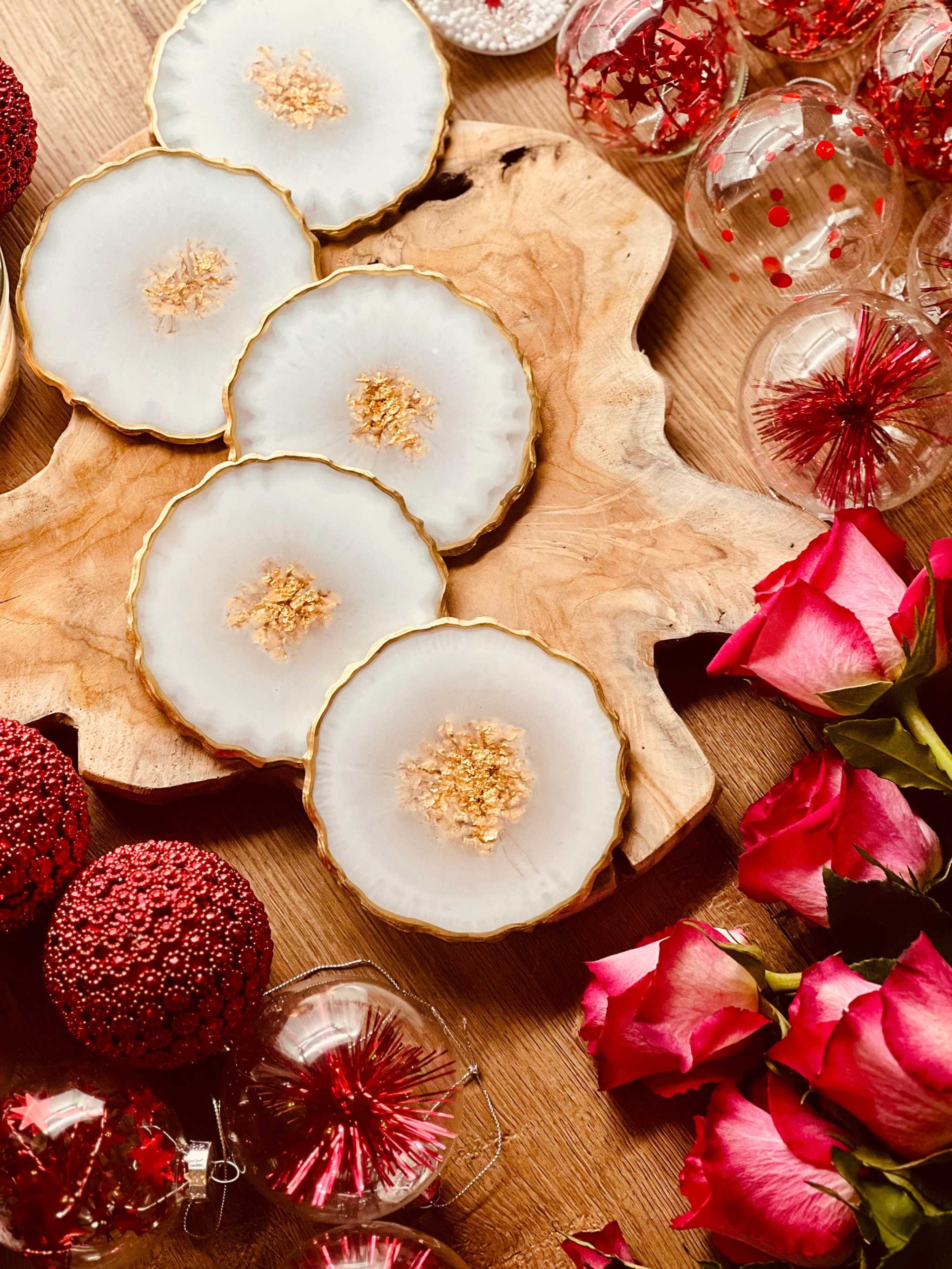 Fünf handgemachte weiße Untersetzer aus Resin mit goldenen Details auf Holzplatte als Dekoration und Geschenkidee