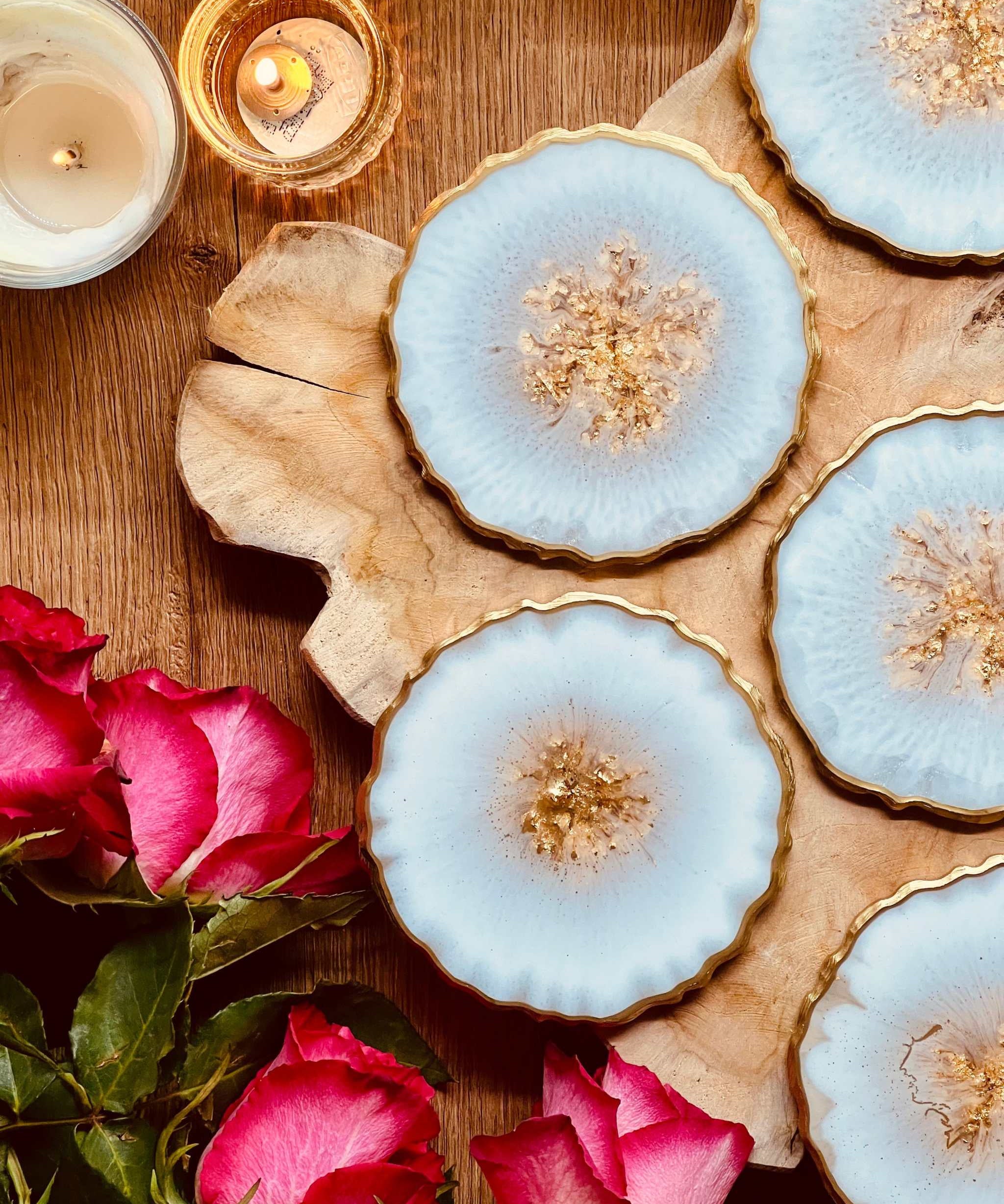 6 handgemachte weiße Resin-Untersetzer mit goldenen Details auf Holztisch mit Kerzen und Rosen
