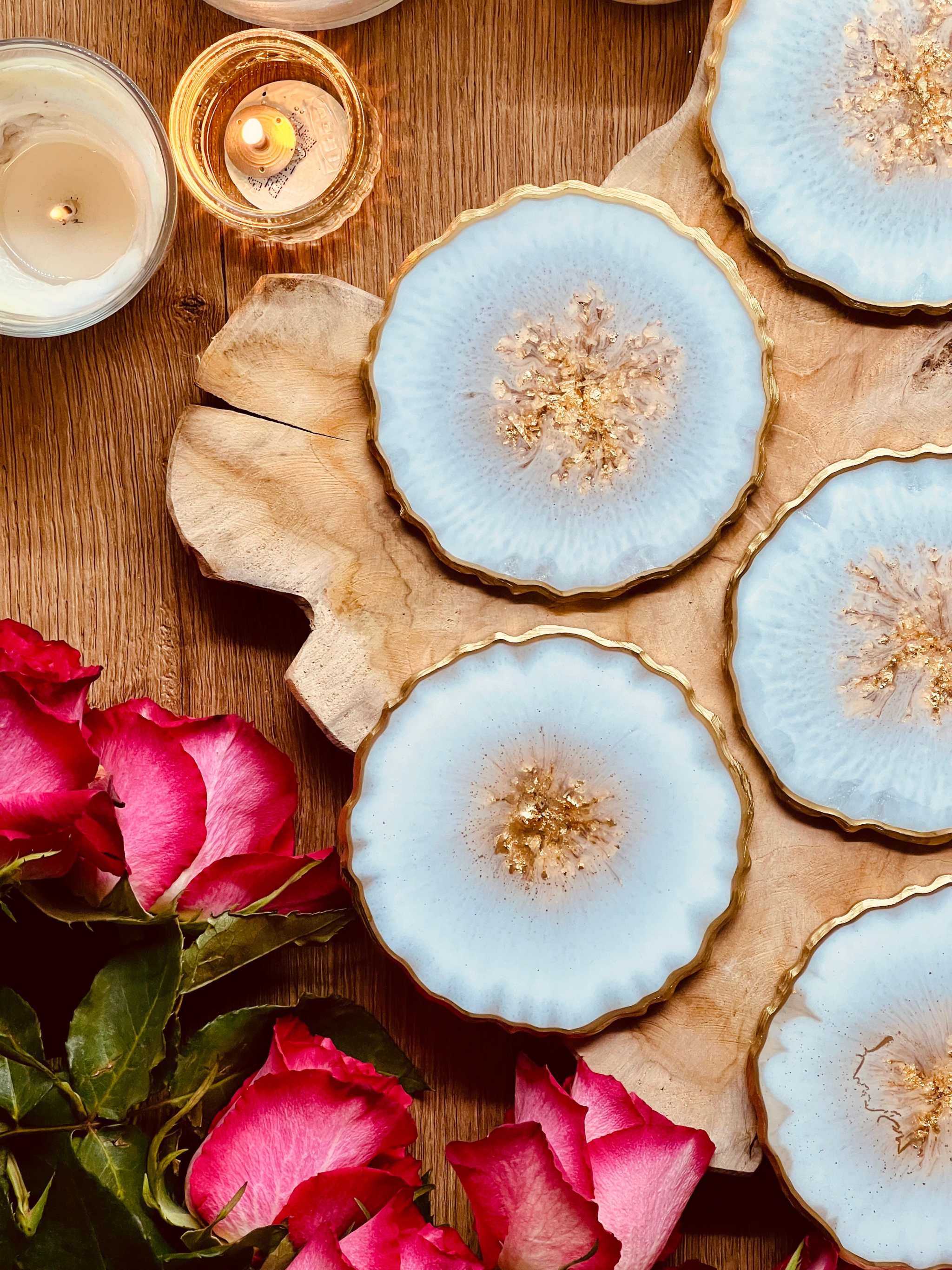 6 handgemachte weiße Resin-Untersetzer mit goldenen Details auf Holztisch mit Kerzen und Rosen