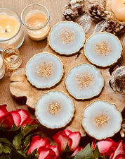 6 Untersetzer aus weißem Resin mit goldenen Details auf Holzplatte dekorativ arrangiert
