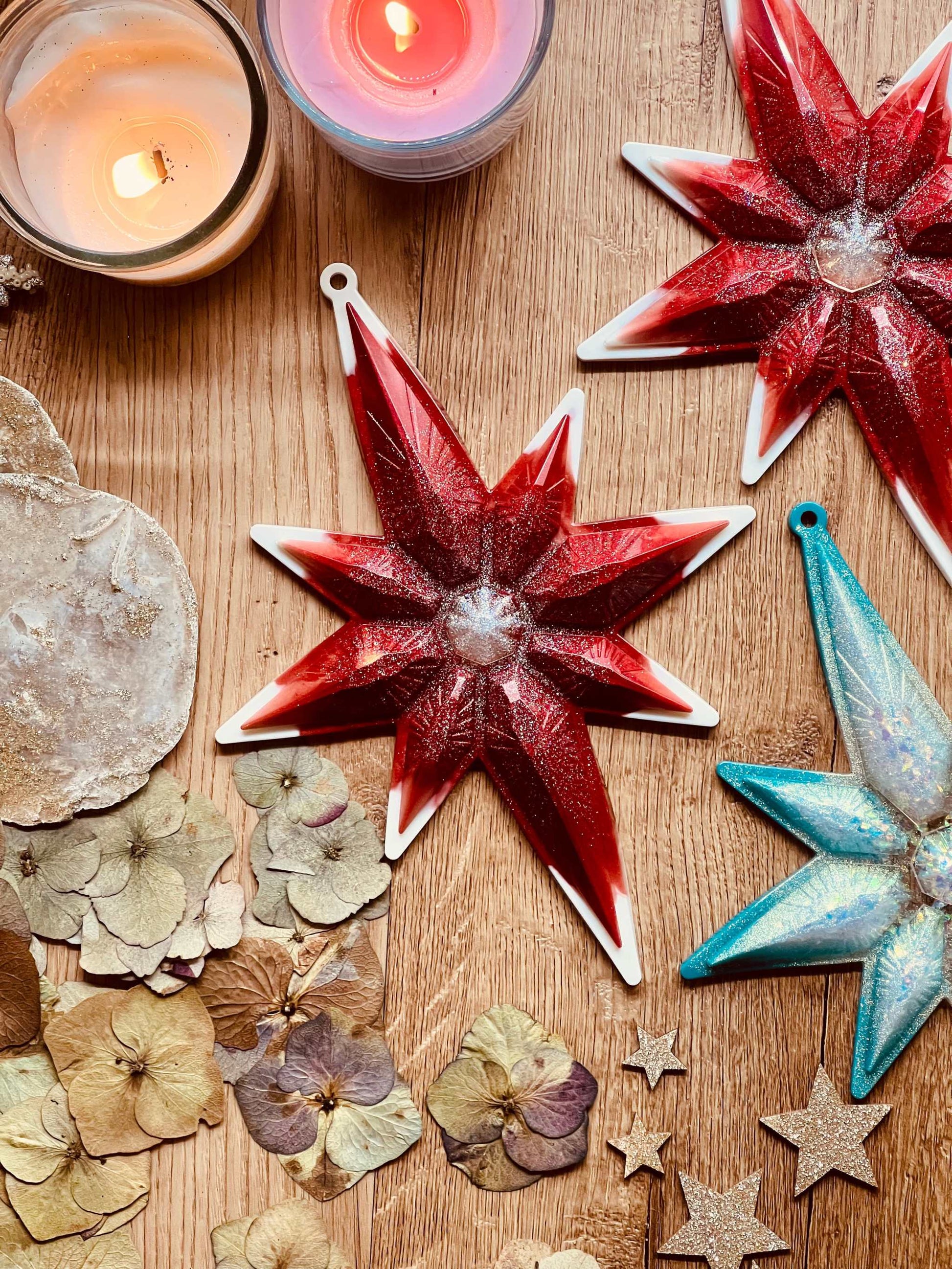 Handmade resin star-shaped Weihnachtsbaumanhänger in red and turquoise with white and silver accents.