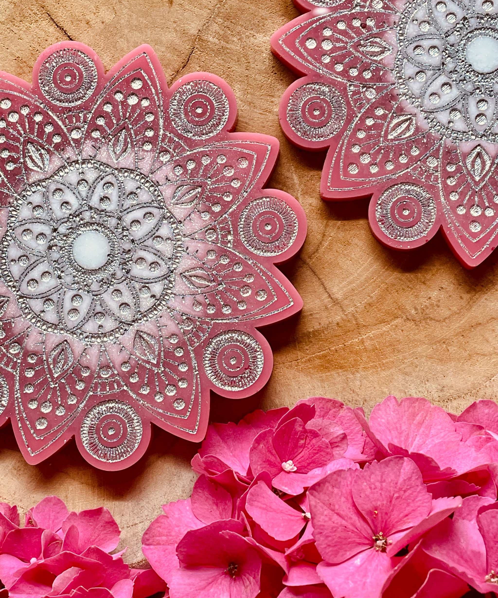 2 handgemachte Mandala Untersetzer aus Resin in Pink mit silbernen Details auf Holzuntergrund mit pinken Blüten