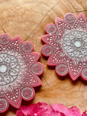 2 handgemachte Mandala Untersetzer aus Resin in Pink mit silbernen Details auf Holzfläche