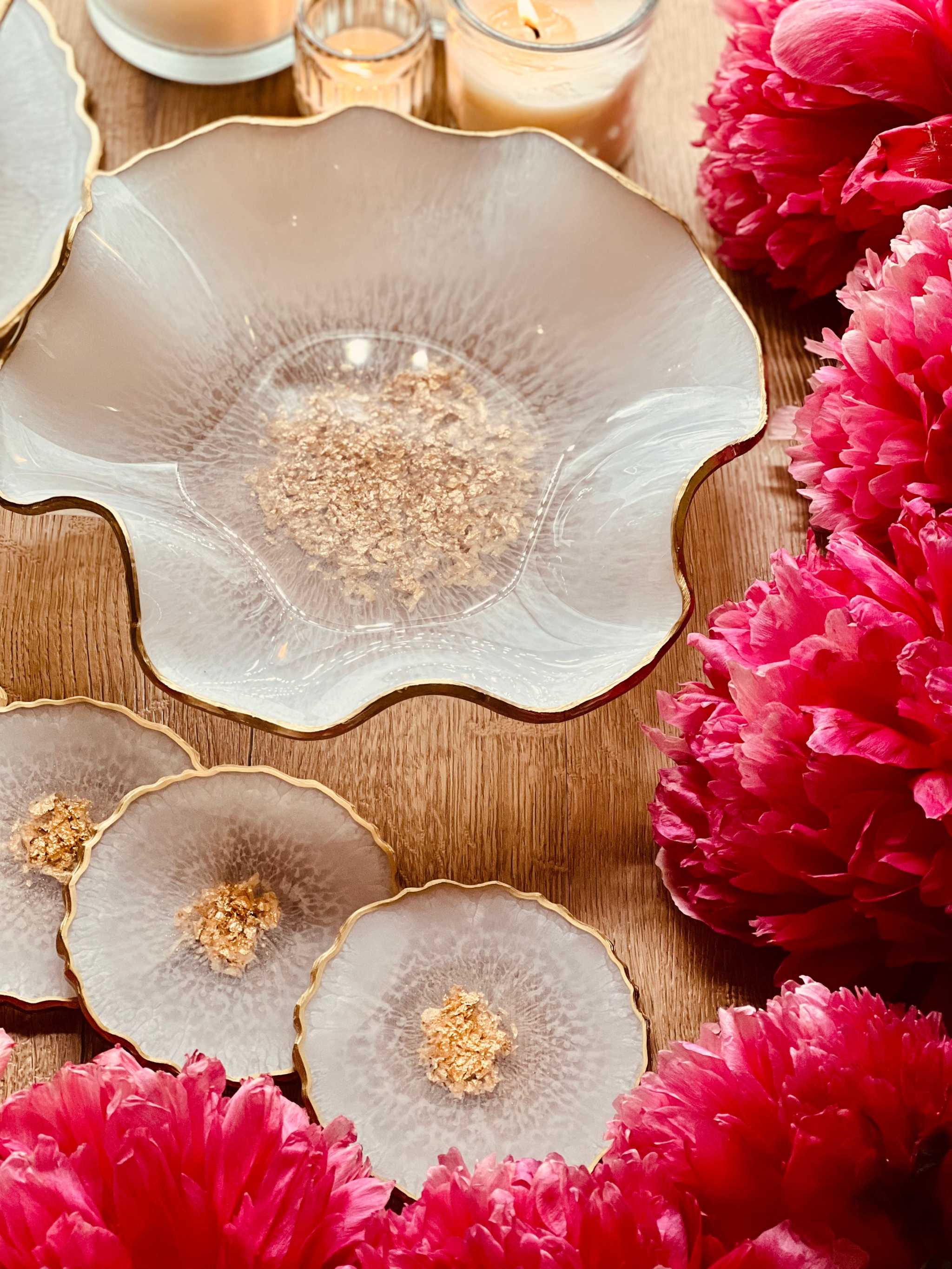 handgemachte Deko Sets aus Resin mit goldenen Akzenten und unregelmäßigen Formen umgeben von pinken Blumen