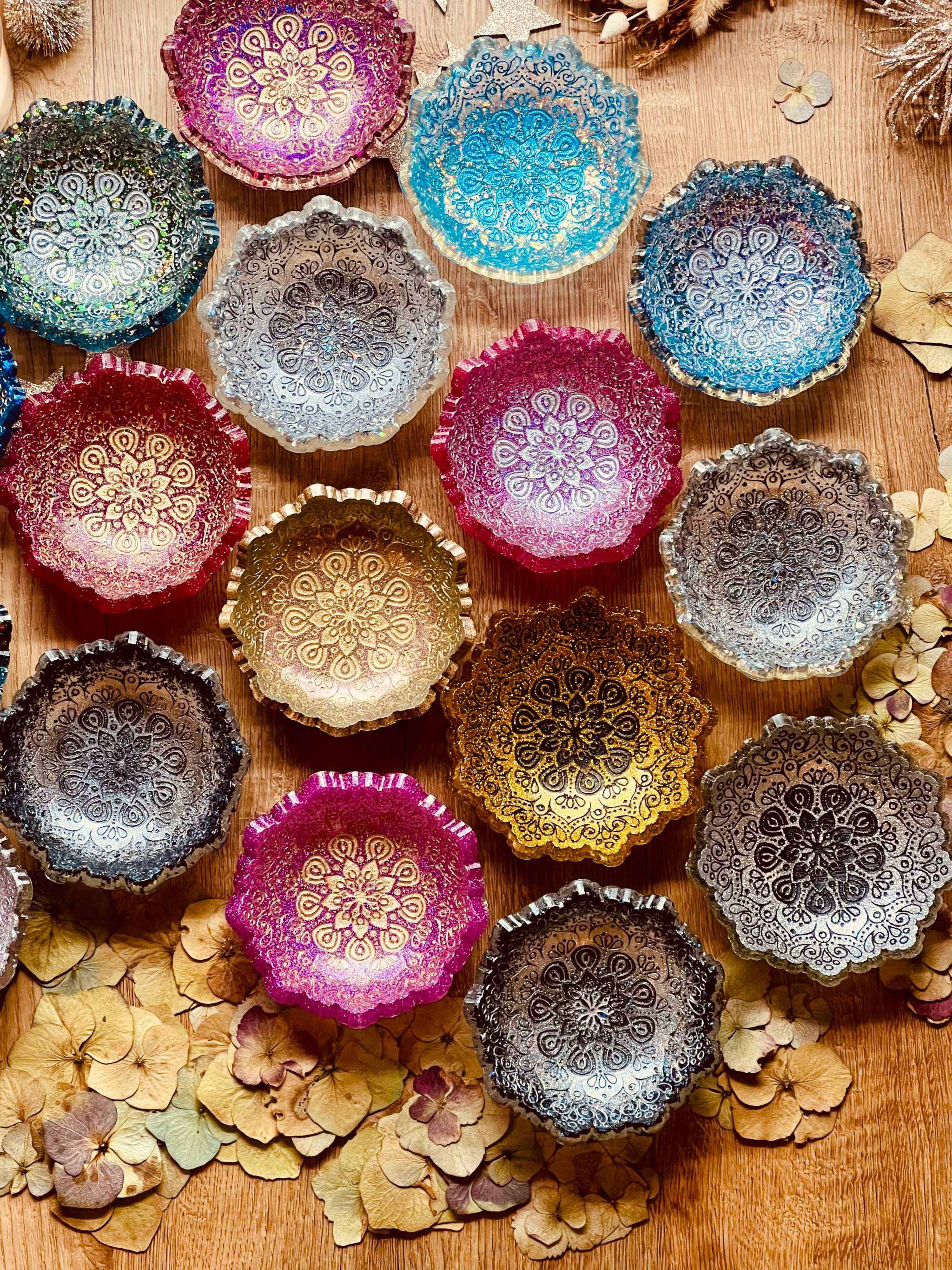 Mehrere handgemachte Mandala Schmuckschalen aus Resin in verschiedenen Farben auf Holzuntergrund dekoriert