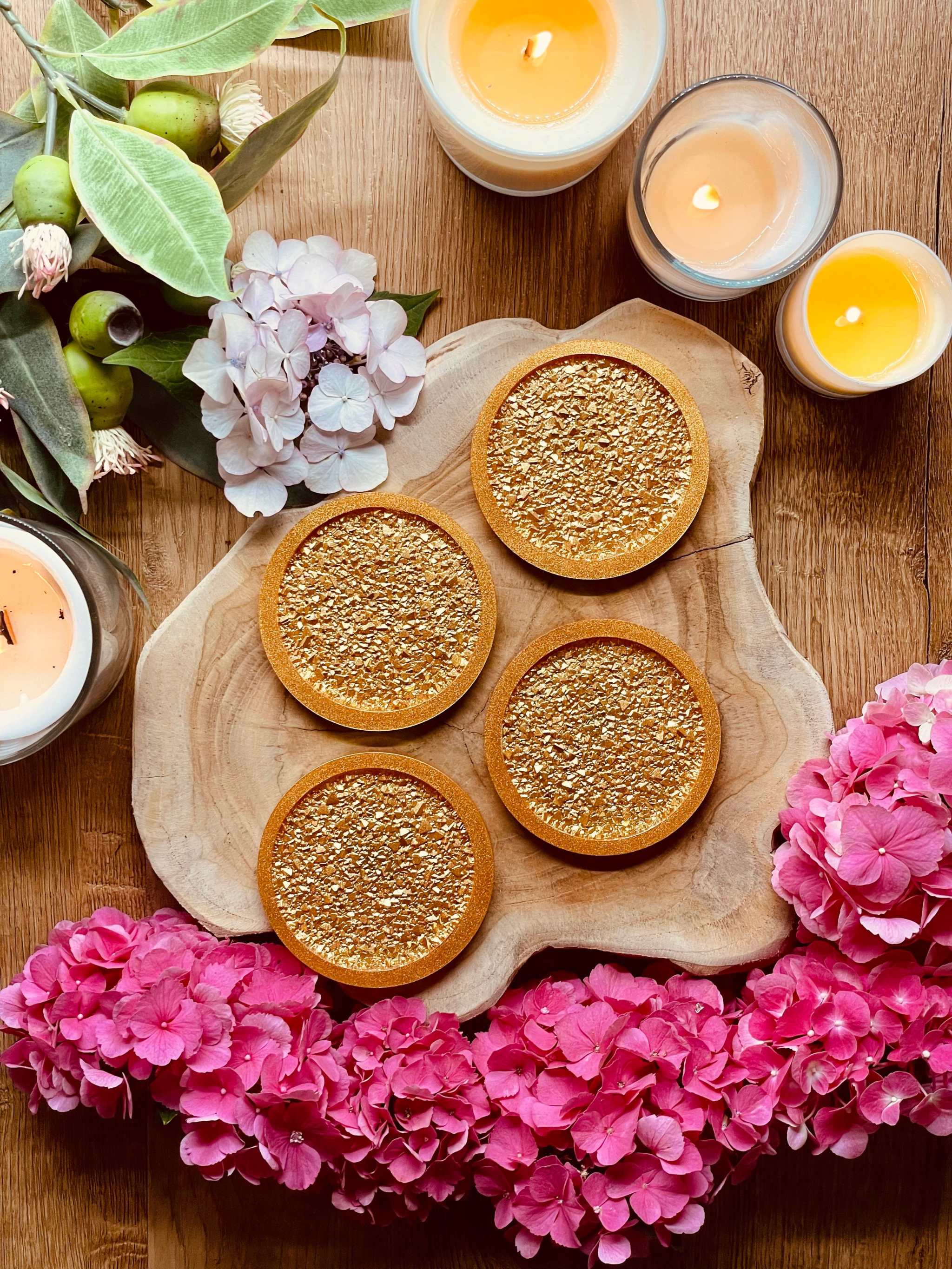 Set mit 4 goldfarbenen Untersetzern aus Resin mit funkelnder Diamantoberfläche auf Holztablett dekoriert mit Kerzen und Blumen