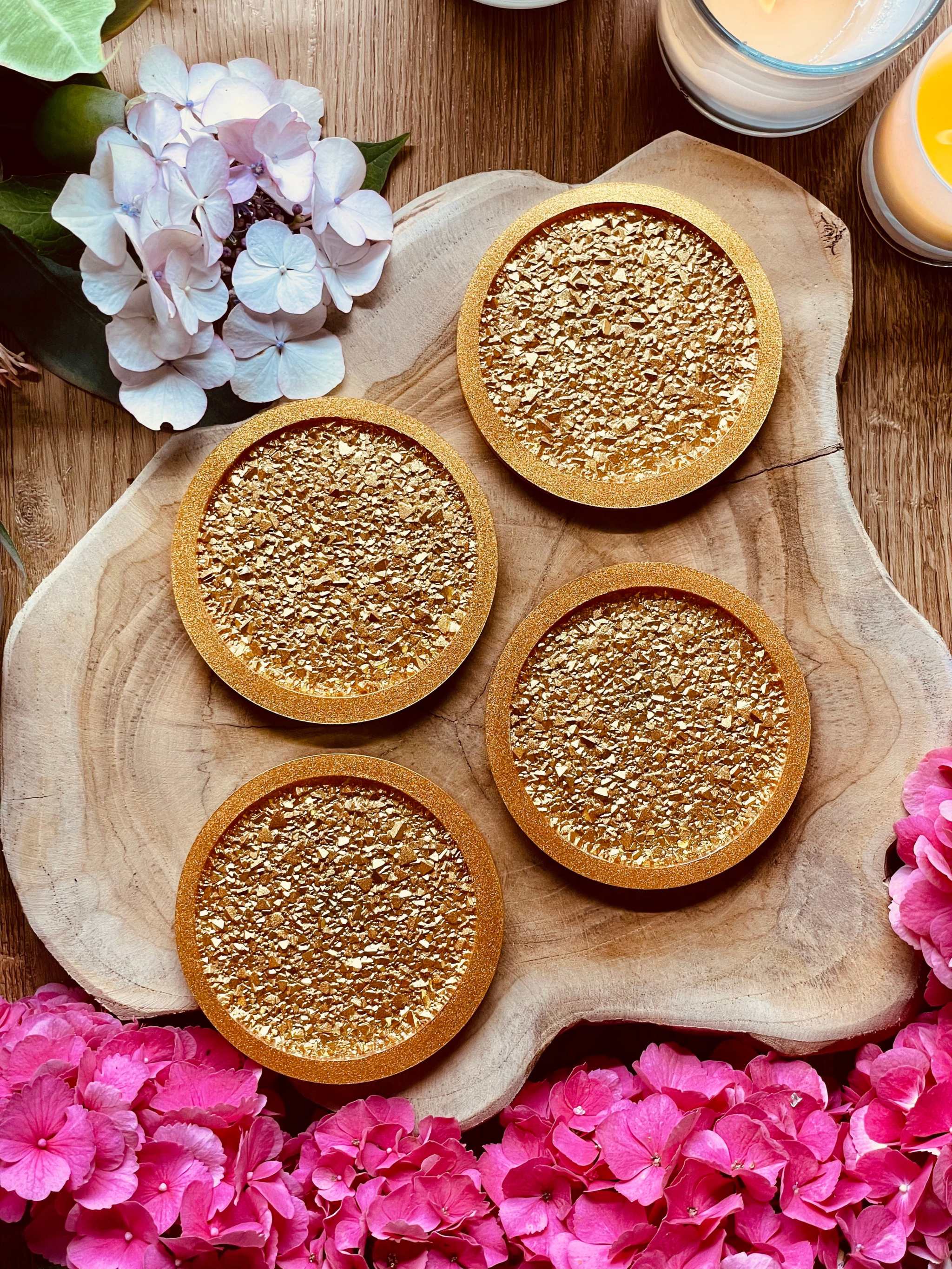 4 goldene Untersetzer aus Resin mit diamantförmiger Oberfläche auf Holztablett, dekoriert mit Blumen und Kerzen