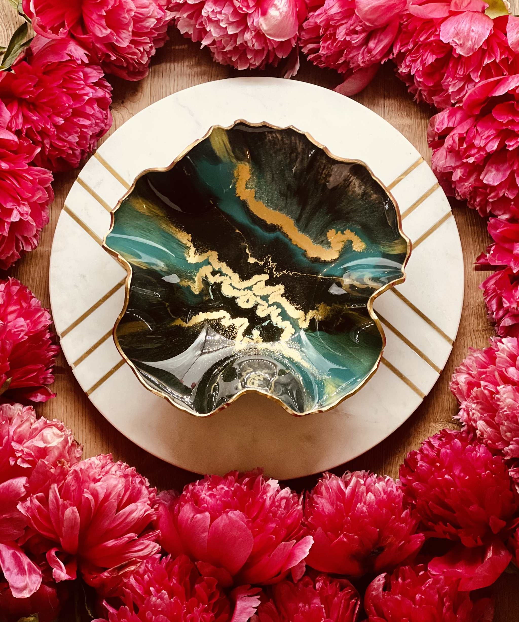 Handgemachte grüne Schale aus Resin mit goldenen Details, dekorativ und einzigartig, umgeben von roten Blüten.