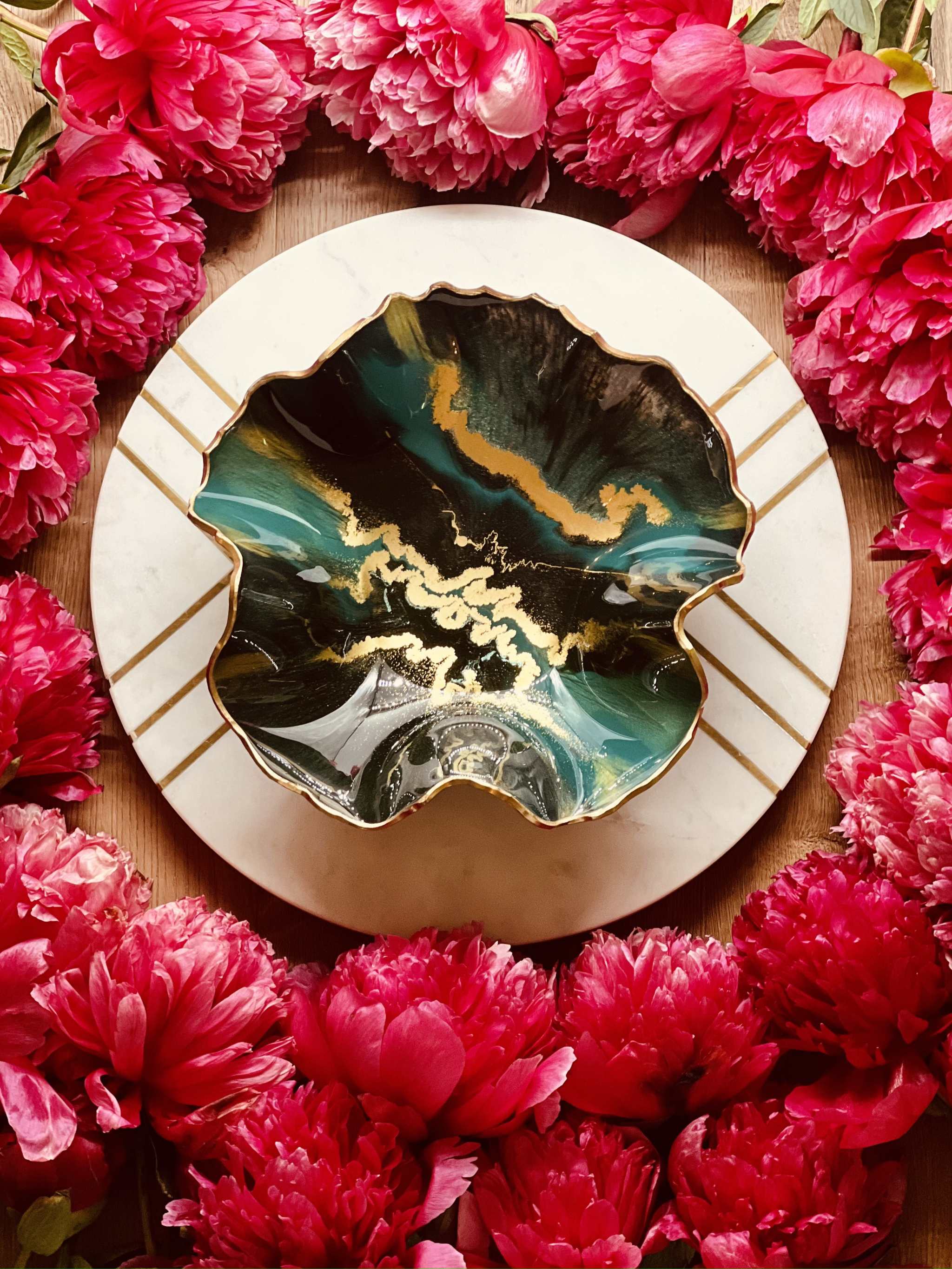 Handgemachte grüne Schale aus Resin mit goldenen Details, dekorativ und einzigartig, umgeben von roten Blüten.