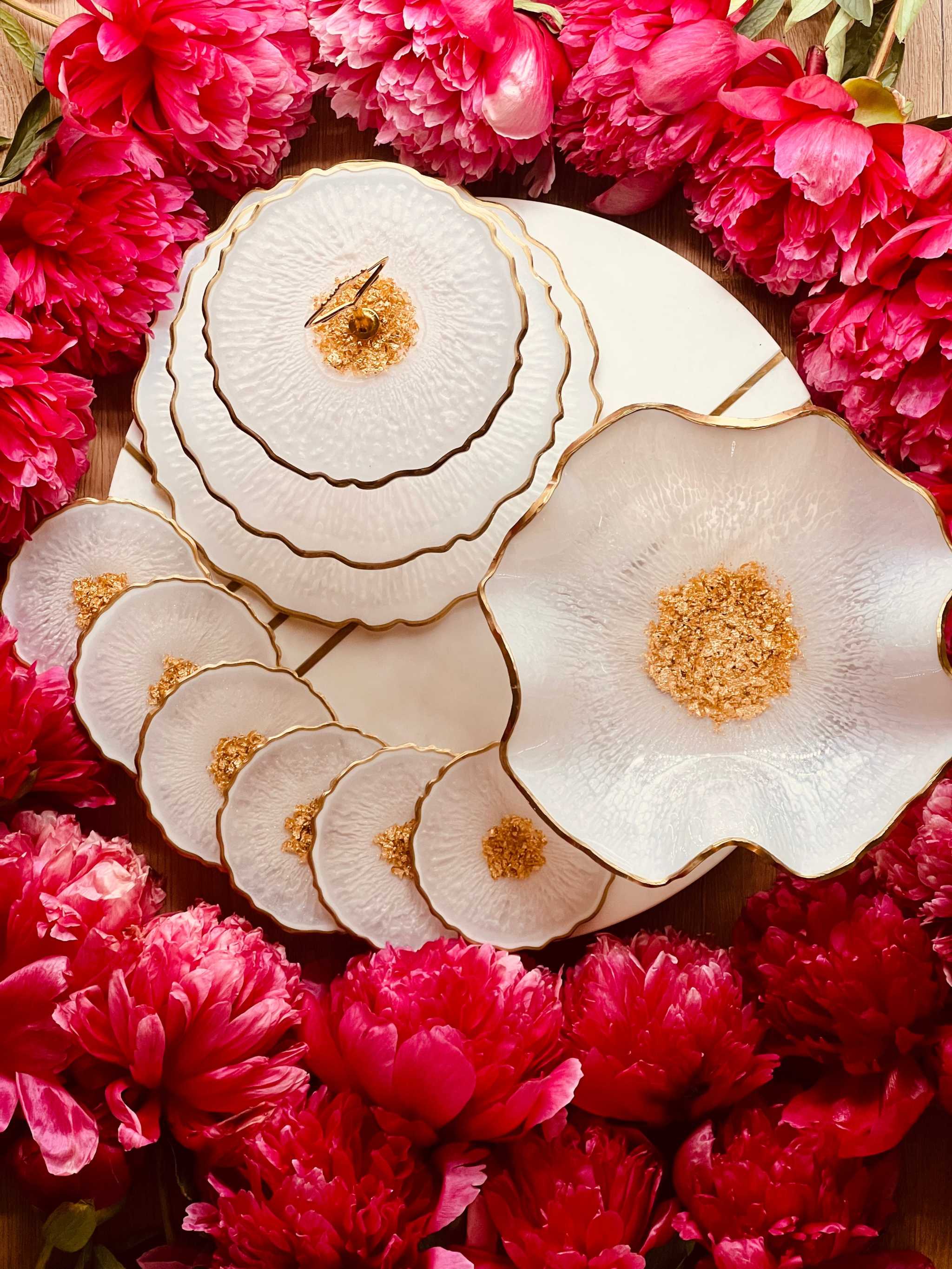 Deko Sets aus Resin handgefertigt mit geschwungenen weißen Schalen und Untersetzern, umgeben von roten Blumen, elegant und individuell gestaltet