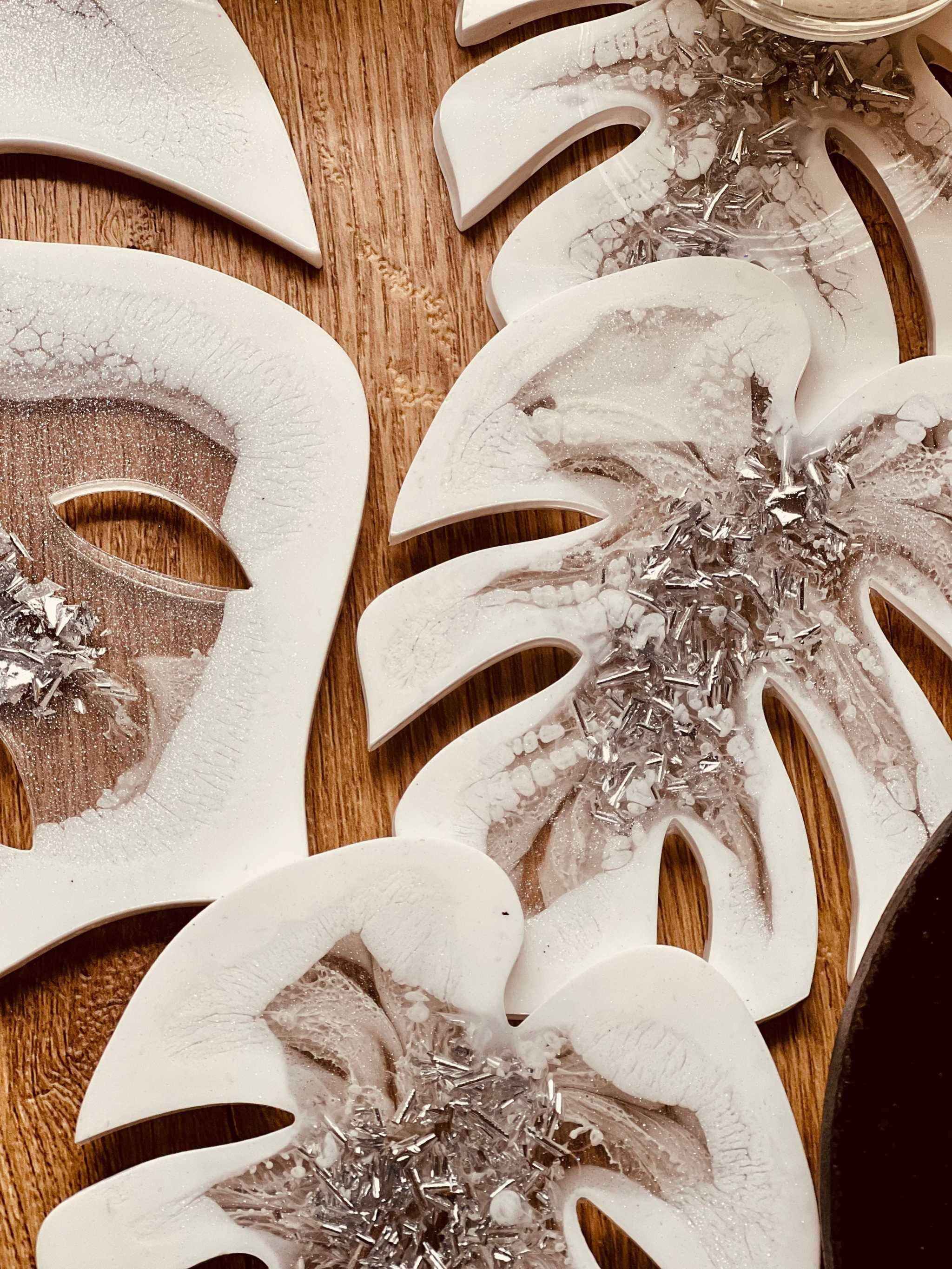 Weißes handgemachtes Resin Tablett und 4 Untersetzer mit silbernen Monstera Details auf Holzuntergrund