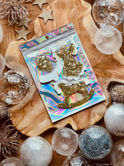 Gold and white resin Christmas tree ornaments with holographic surface on wooden background.