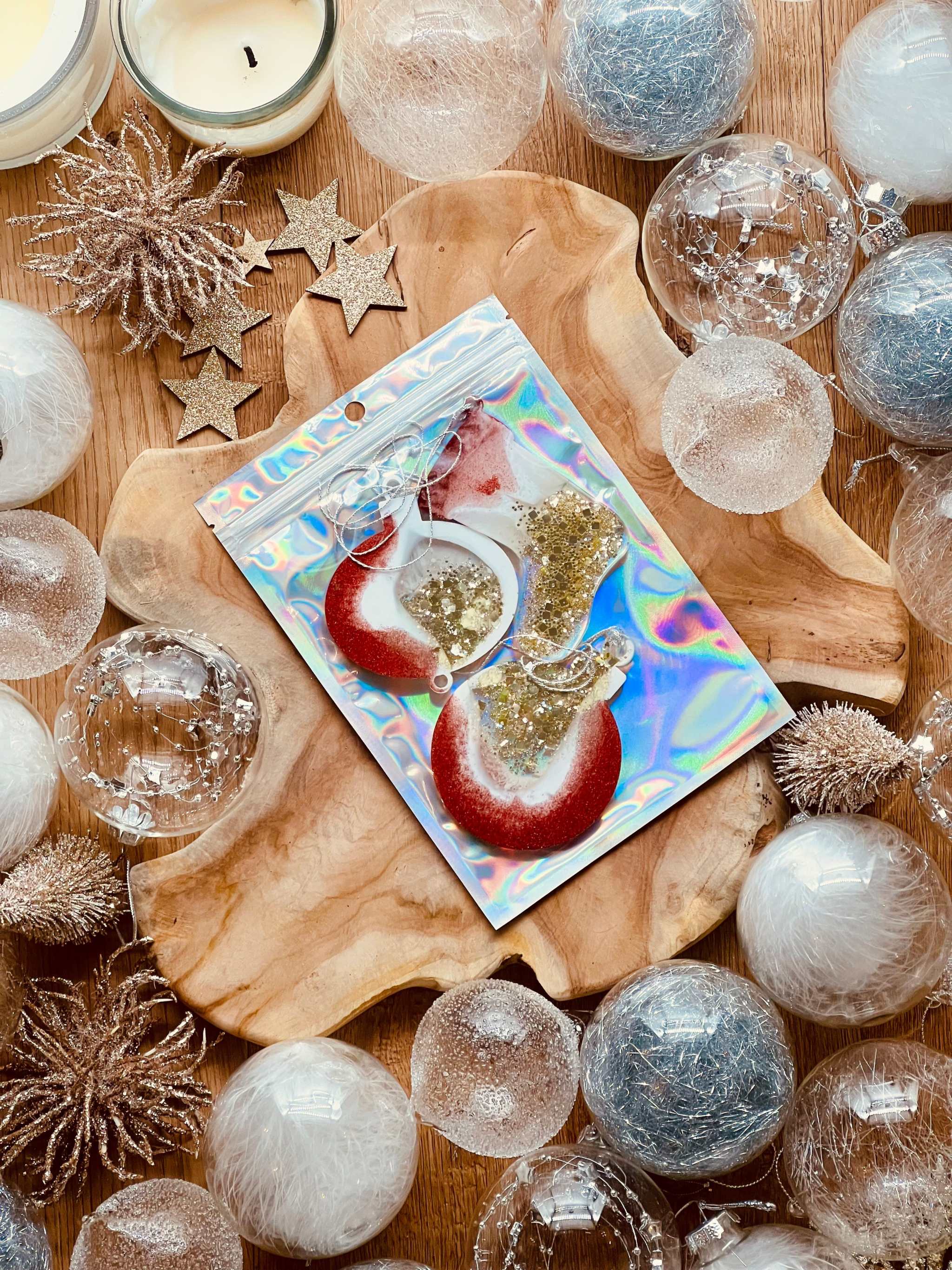 Weihnachtsbaumanhänger aus Resin in Rot, Gold und Weiß mit holographischer Oberfläche auf Holztablett.