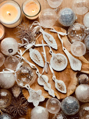 Handmade white and silver resin Christmas tree ornaments set of 7 displayed on a wooden surface.