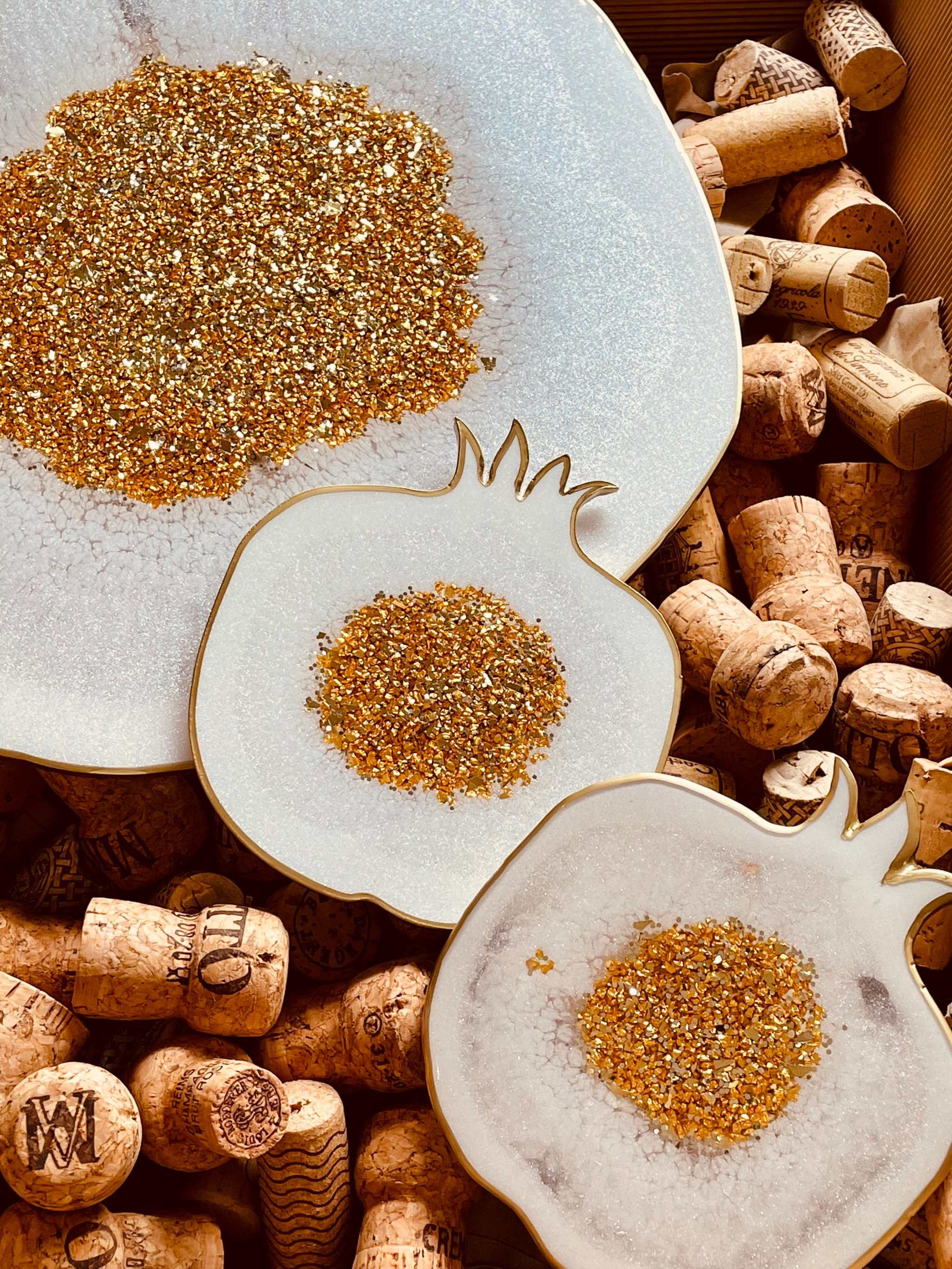 weißes Resin Tablett und 2 Untersetzer mit goldenen Granatapfel-Details auf Weinkorken