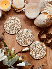 handgemachte goldene untersetzer aus clay mit geflochtenem muster und kerzen dekor auf holztisch