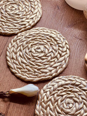 Handgemachter goldener Untersetzer aus Clay mit geflochtenem Design auf Holztisch