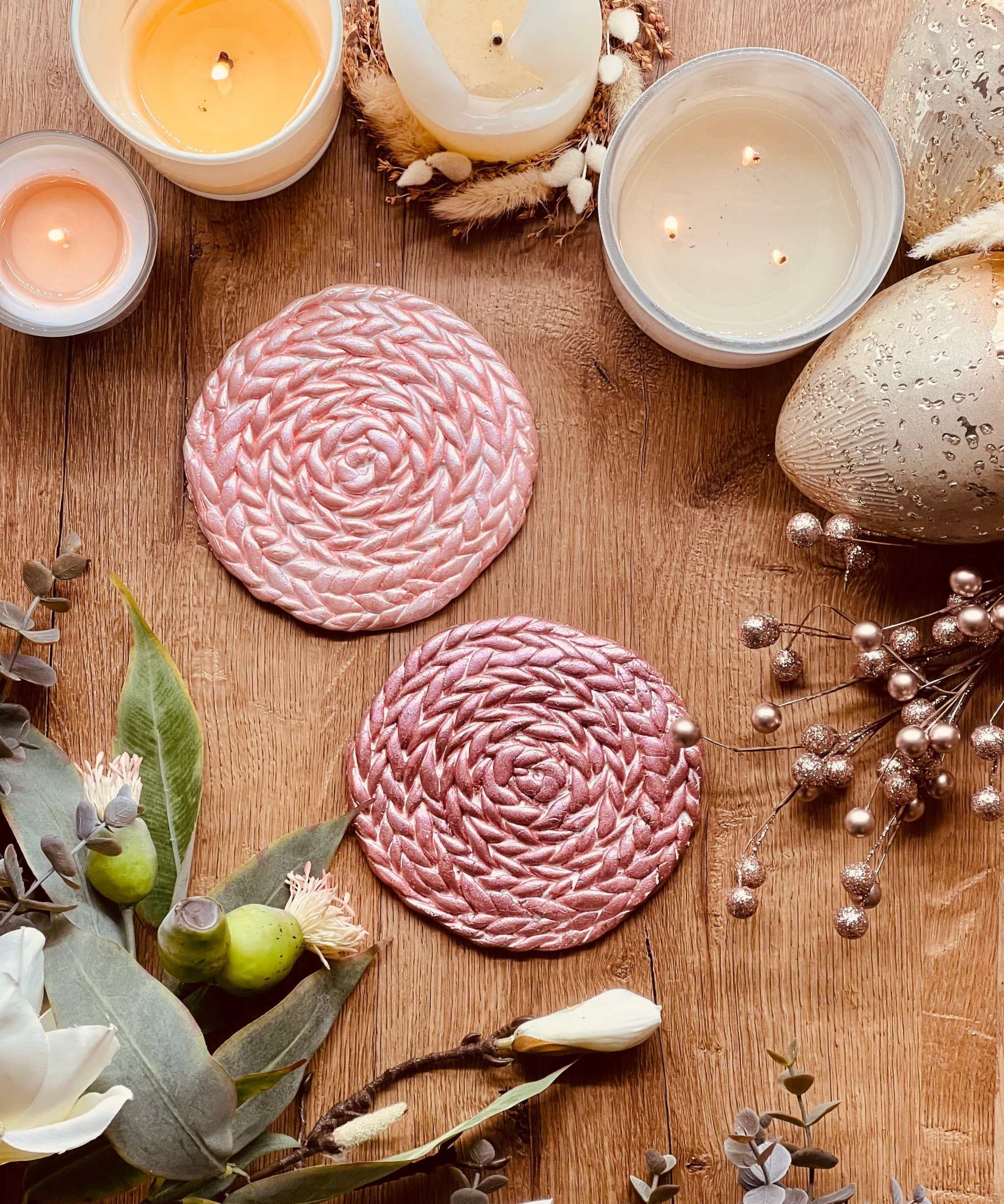 2 handgemachte Untersetzer aus rosa und pinkem Clay als dekoratives Set auf Holztisch mit Kerzen und Deko