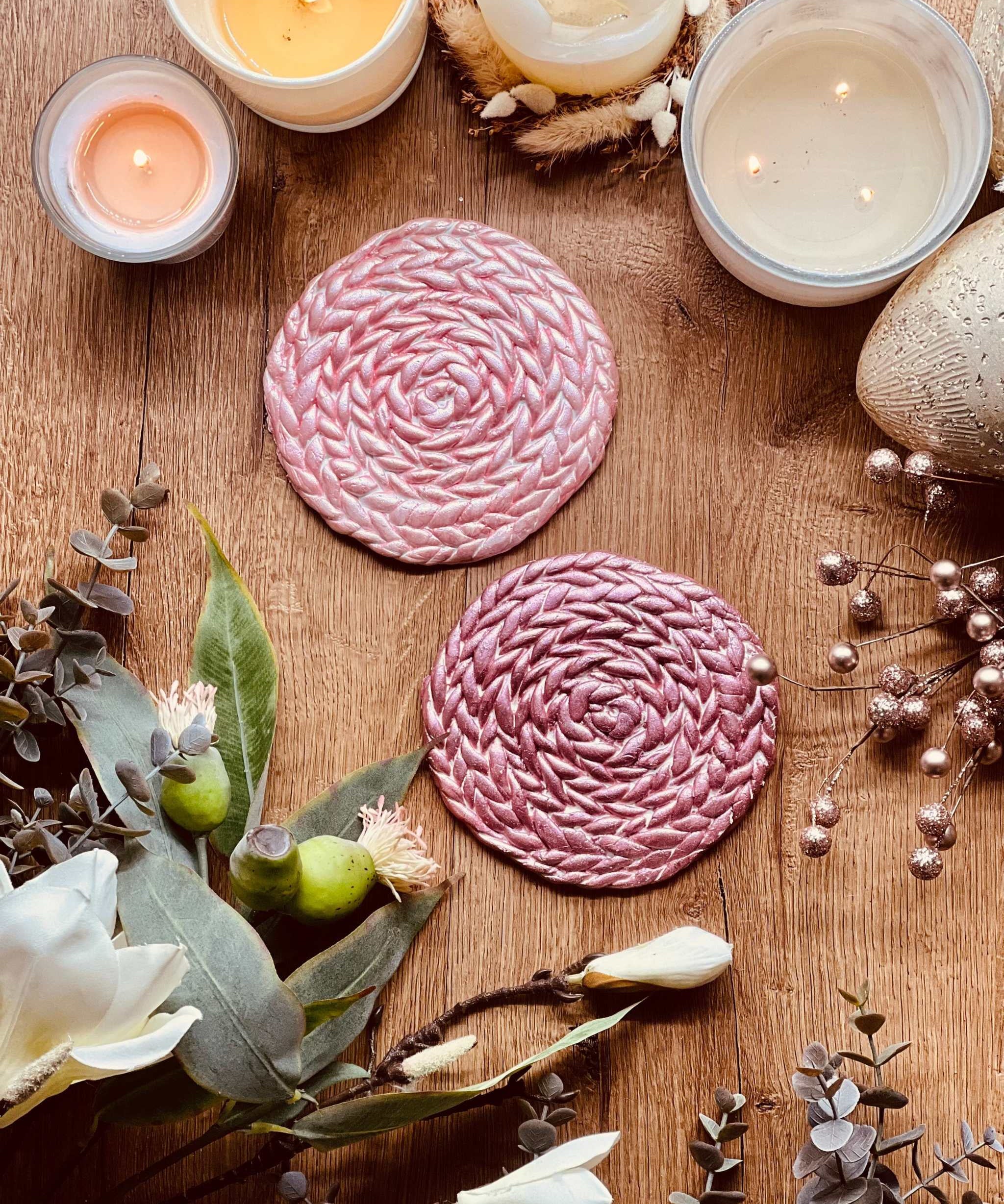 2 handgemachte Untersetzer aus rosa und pinkem Clay auf Holztisch mit Kerzen und Blumen dekoriert