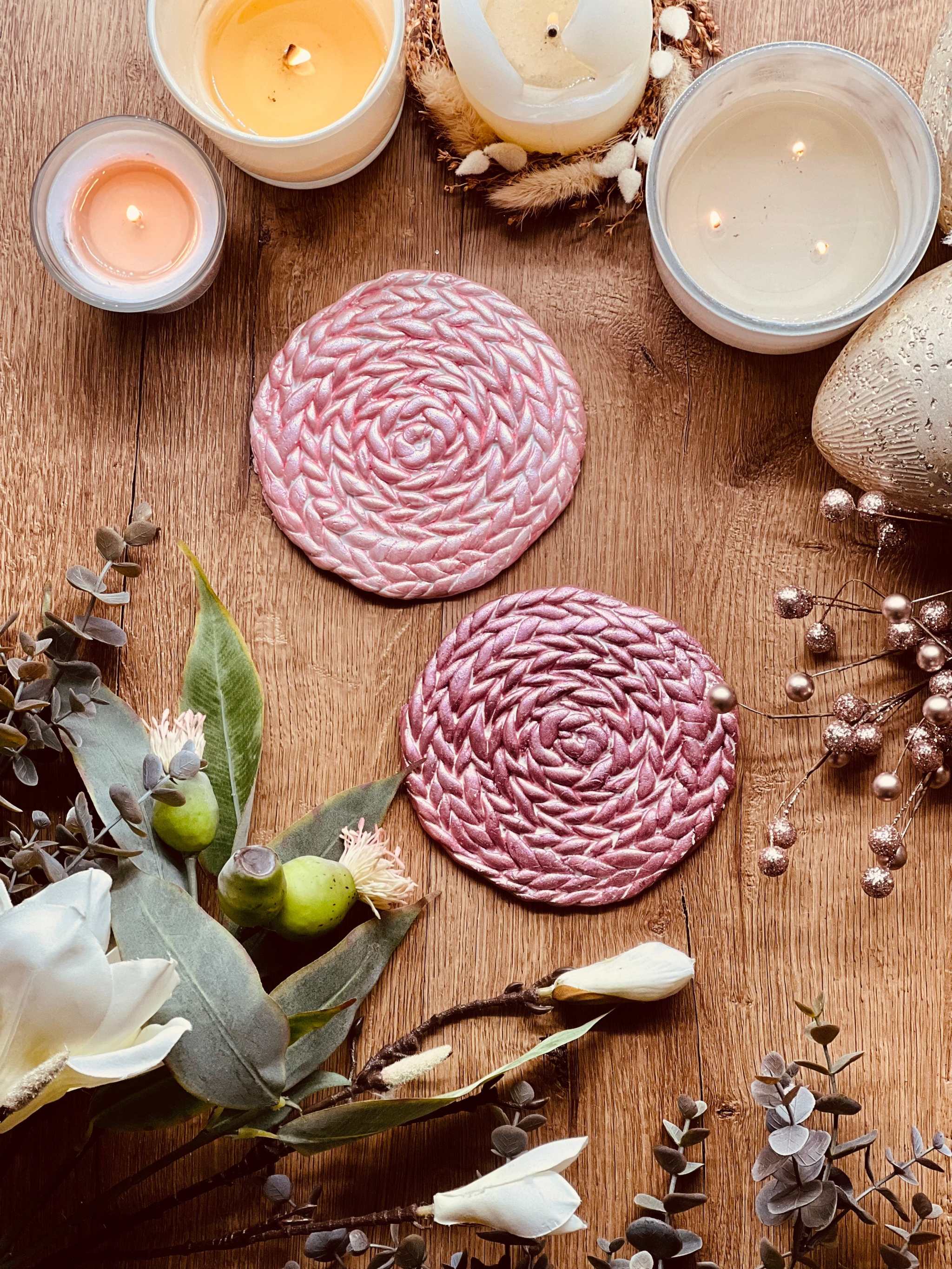 2 handgemachte Untersetzer aus rosa und pinkem Clay auf Holztisch mit Kerzen und Blumen dekoriert