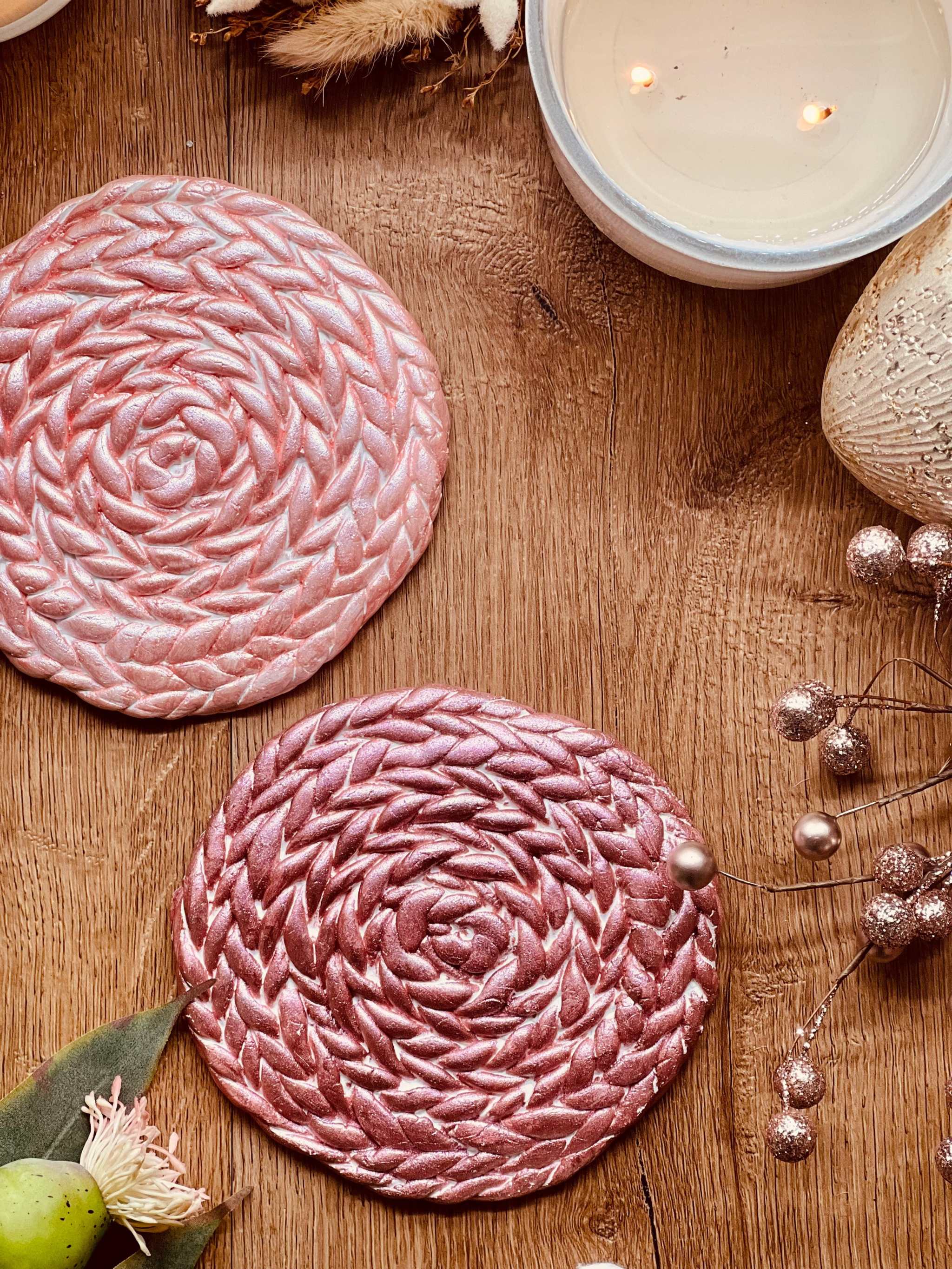 2 handgemachte Untersetzer aus Clay in Rosa und Pink auf Holztisch dekorativ platziert