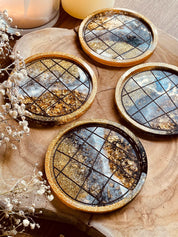 Vier handgemachte Untersetzer aus Resin in Schwarz Weiß Gold mit LineArt Oberfläche auf Holzplatte
