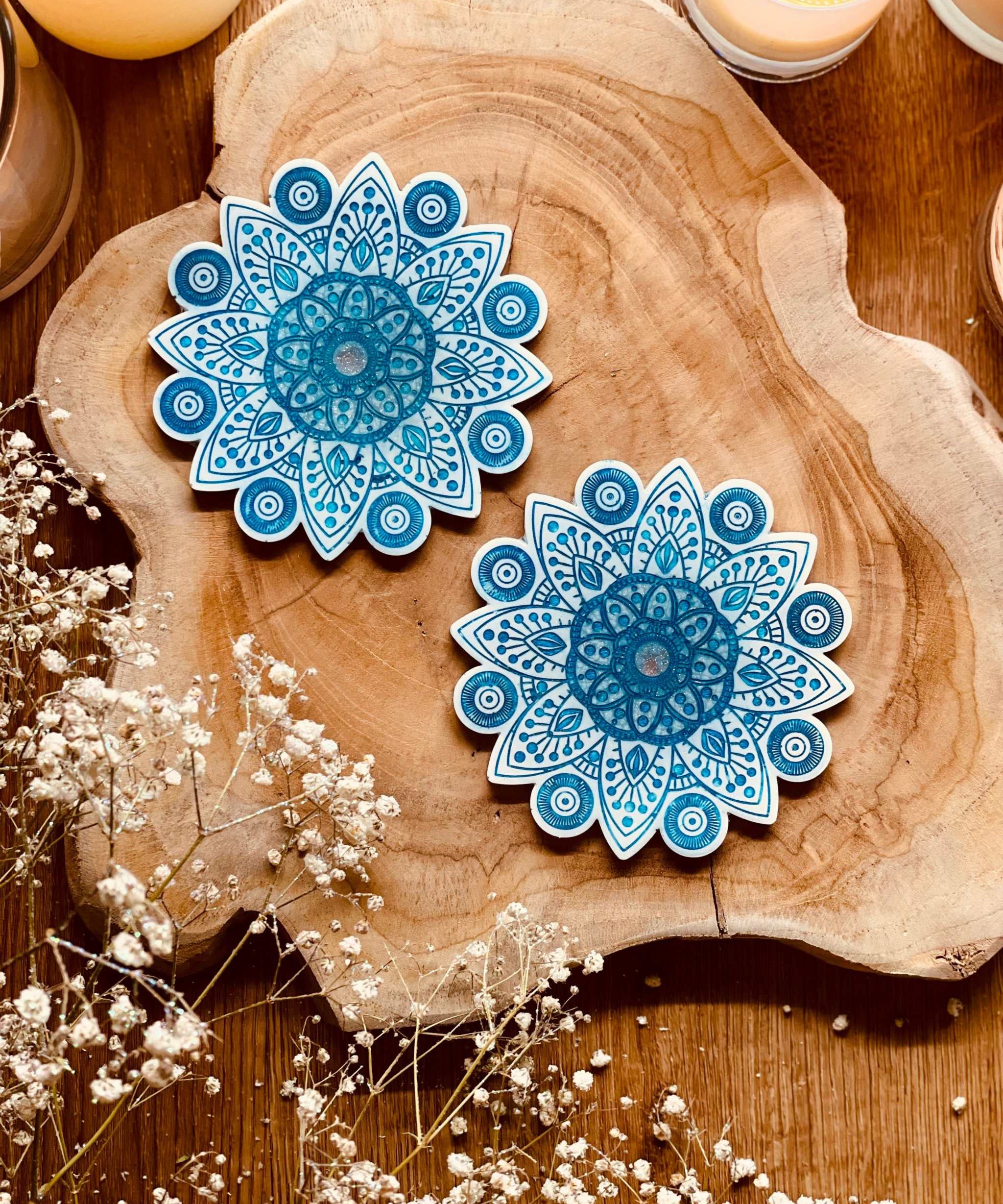 2 Mandala Untersetzer aus Resin in Weiss mit blauen Details auf Holzunterlage dekorativ arrangiert