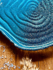 Handgemachte Schale aus Resin in glänzenden Blautönen auf Holztisch
