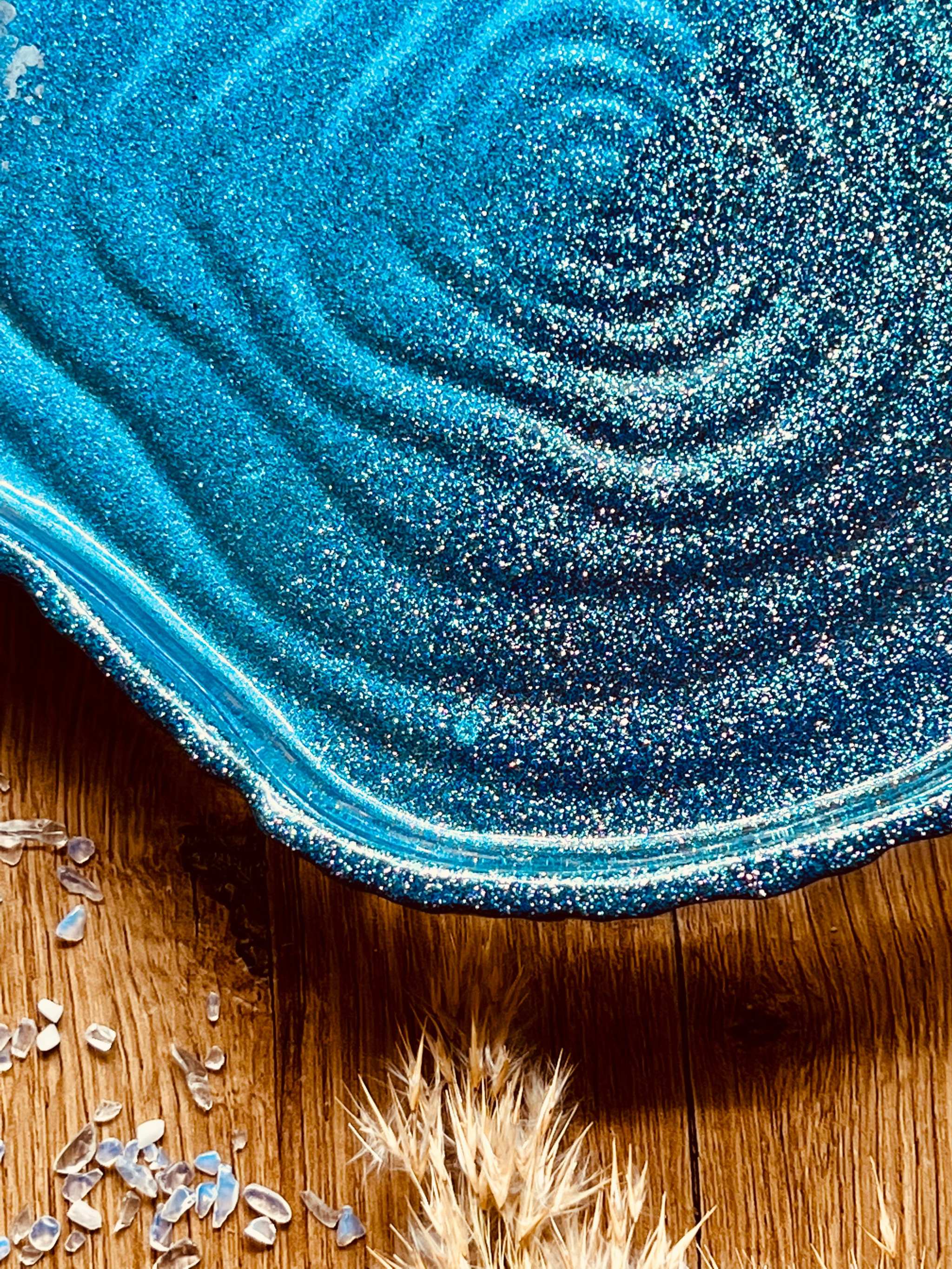 Handgemachte Schale aus Resin in glänzenden Blautönen auf Holztisch