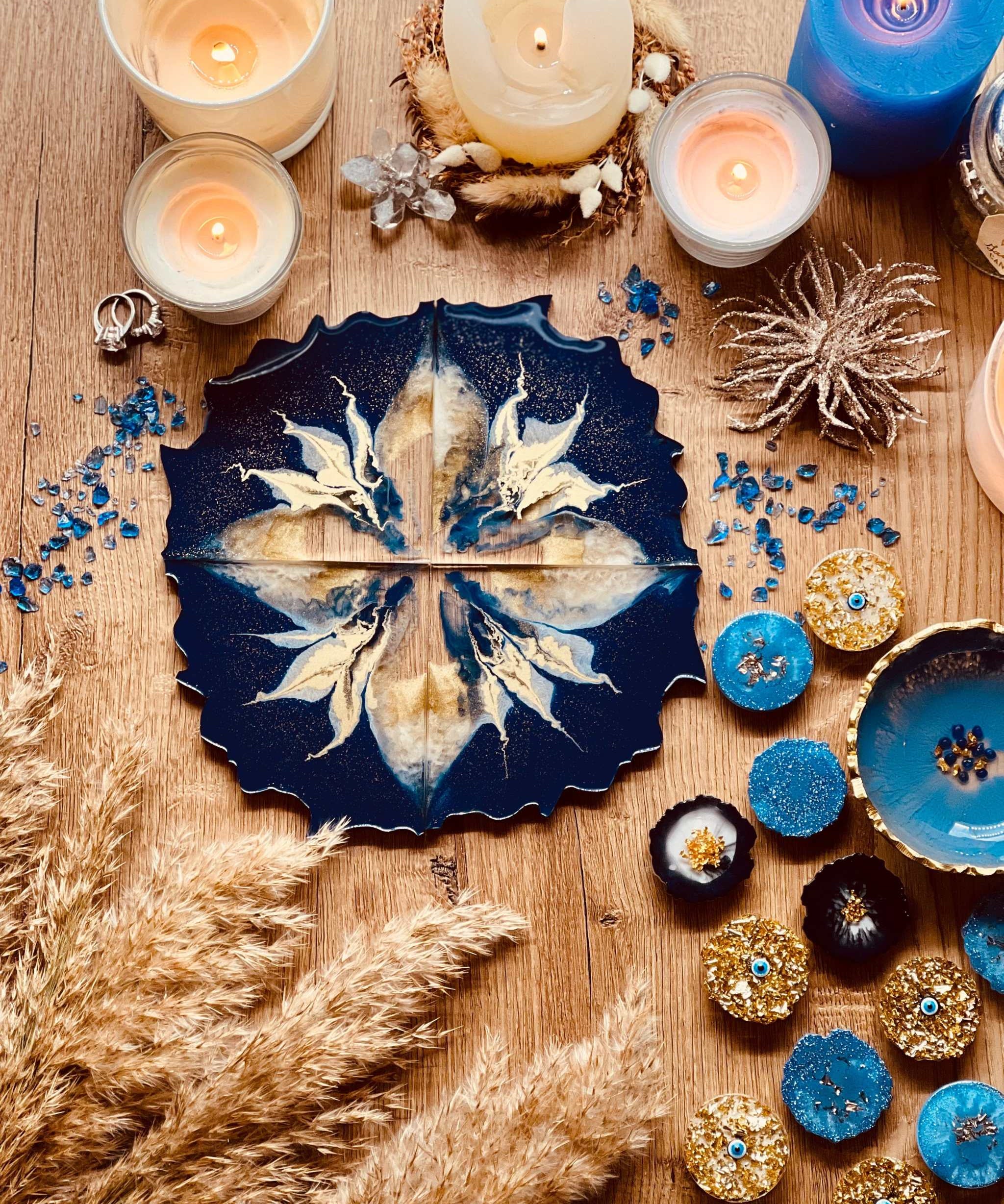 4 handgemachte blaue Resin Untersetzer mit goldenen Details dekorativ auf Holztisch mit Kerzen und Snacks