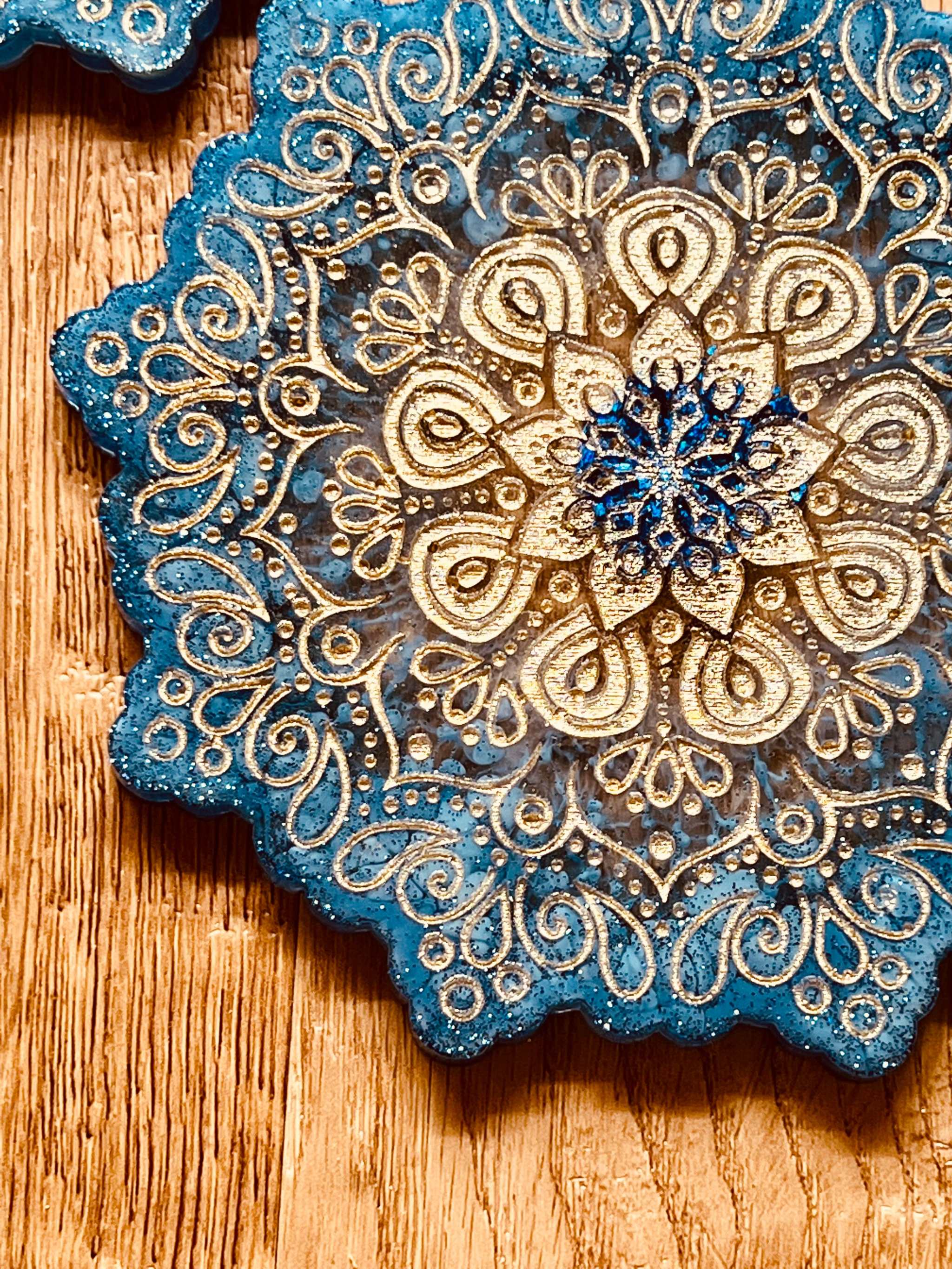 4 Mandala Untersetzer aus blauem Resin mit goldenen Details und filigranem Mandala Design auf Holztisch