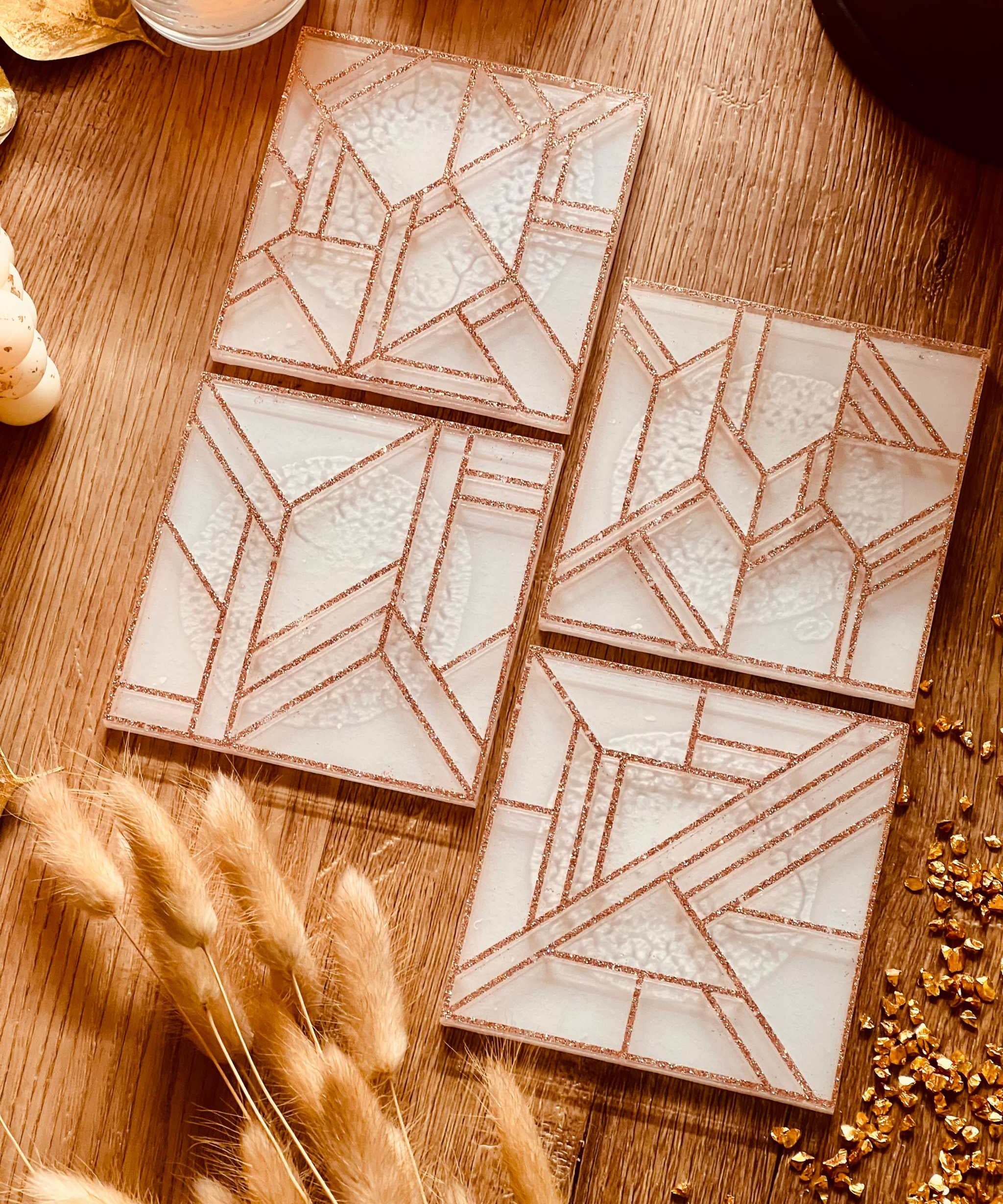 Set aus vier modernen weißen Untersetzern aus Resin mit goldfarbenem 3D-Design auf Holztisch