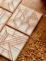 moderne weiße Untersetzer aus Resin mit goldfarbenem 3D Muster auf Holztisch