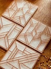 4 moderne weiße Resin Untersetzer mit goldenem 3D Design in eckigem Muster auf Holztisch