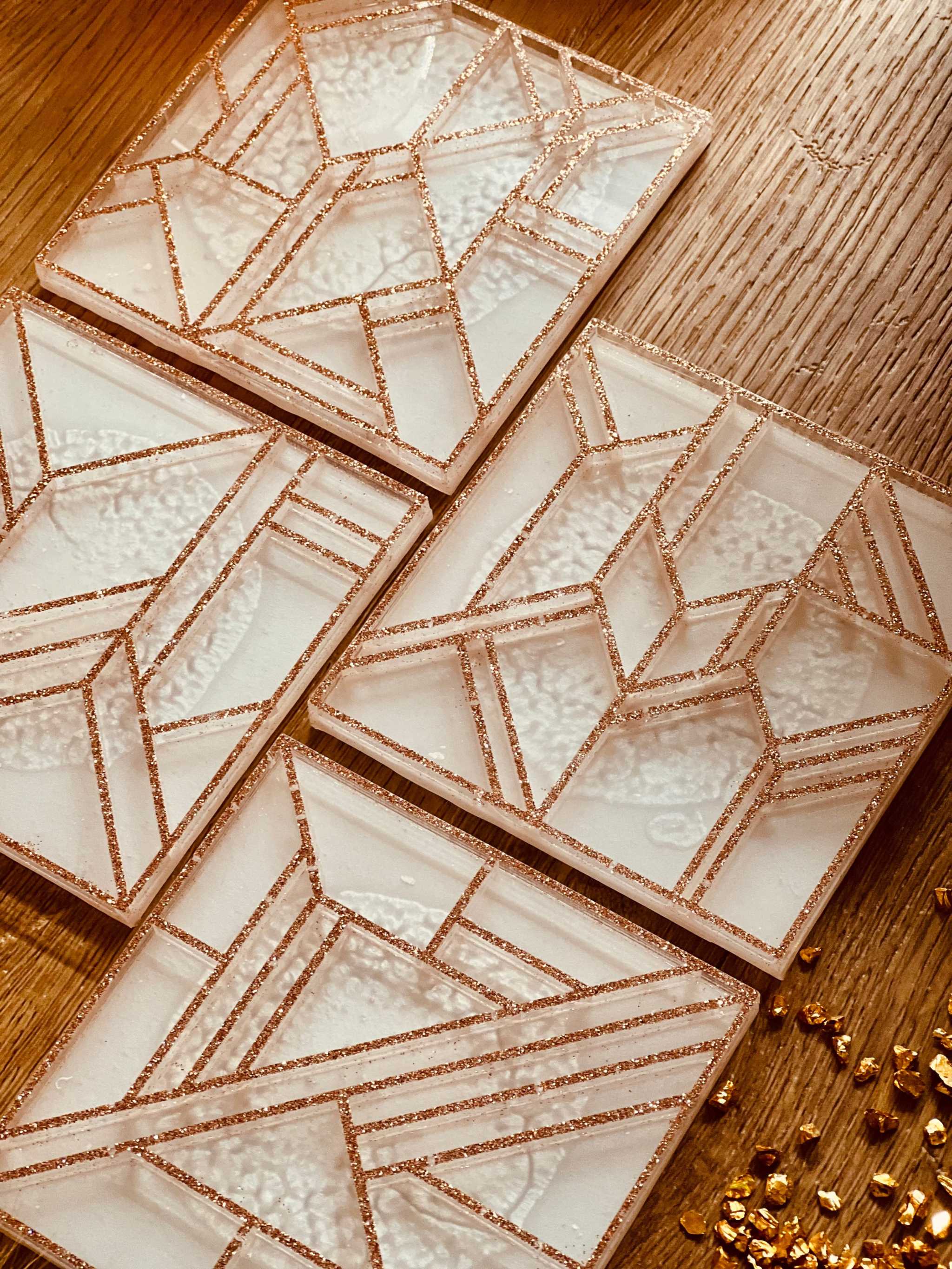 4 moderne weiße Resin Untersetzer mit goldenem 3D Design in eckigem Muster auf Holztisch