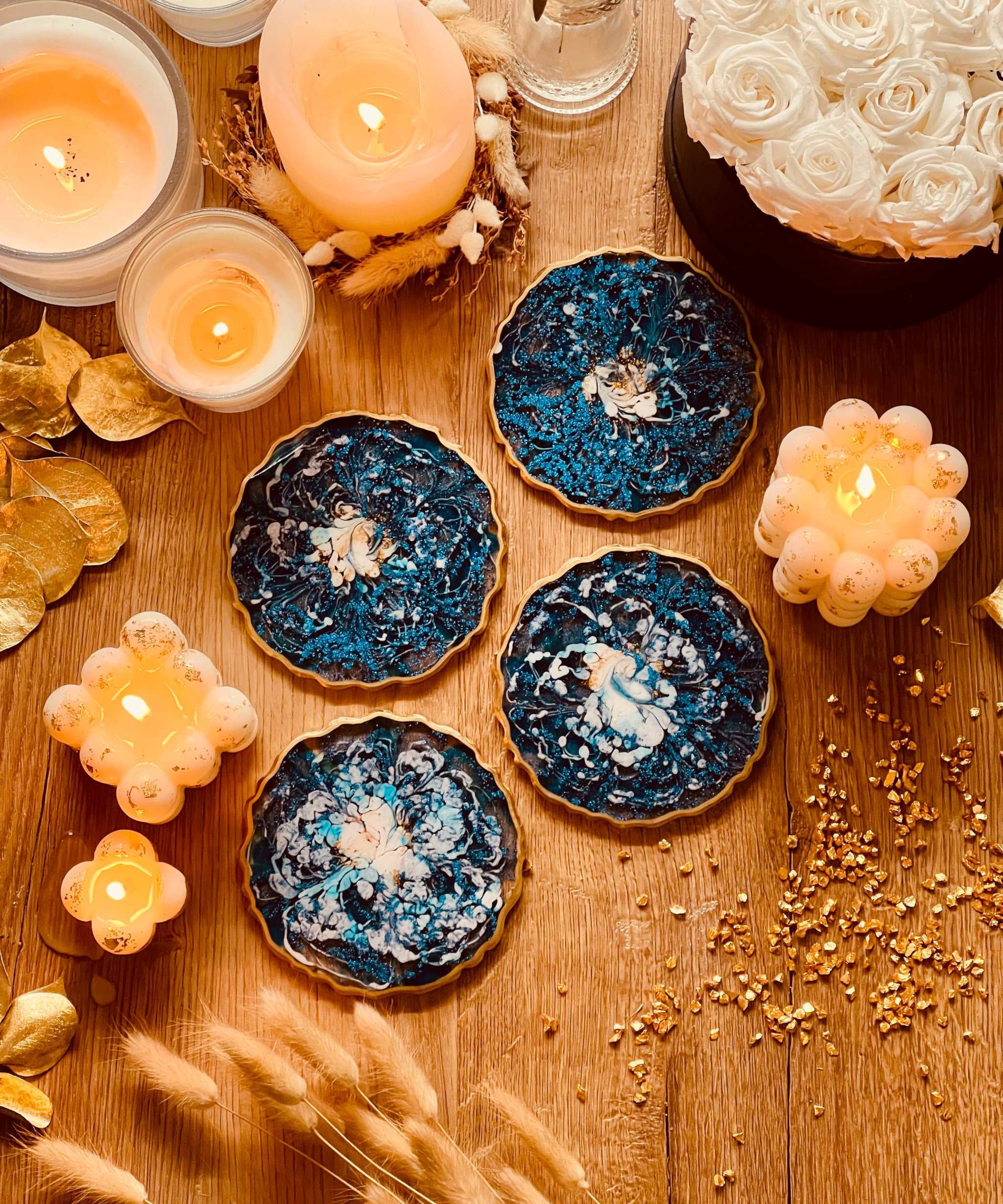 4 Untersetzer aus Resin in Blau mit goldenen Details auf Holztisch neben Kerzen und Dekoration