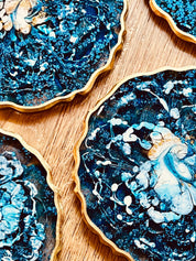 4 handgemachte blaue Untersetzer aus Resin mit goldenen Details auf Holzuntergrund