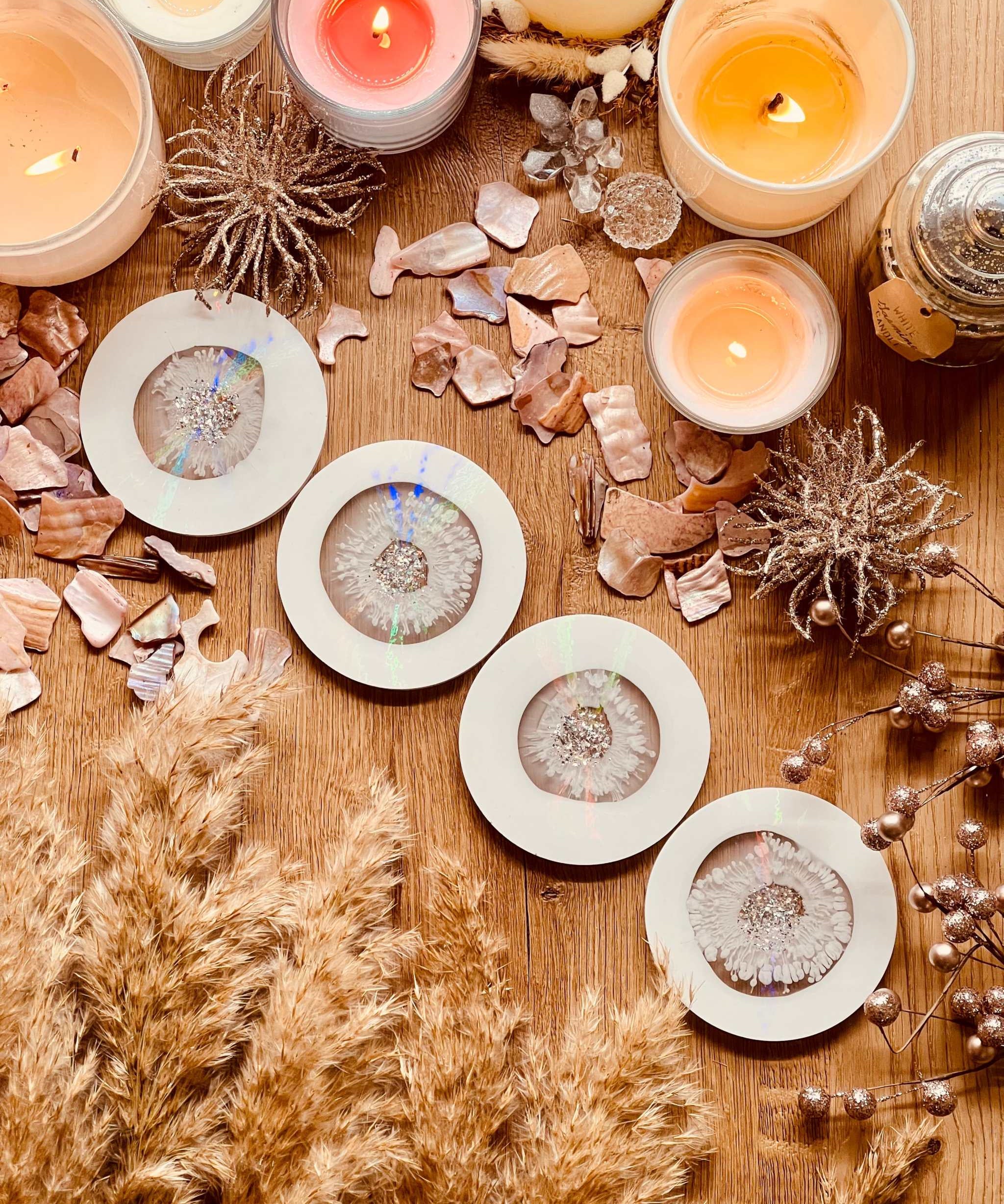 5 Untersetzer aus weißem Resin mit goldenen und holographischen Details handgemacht auf Holztisch mit Kerzen und Deko