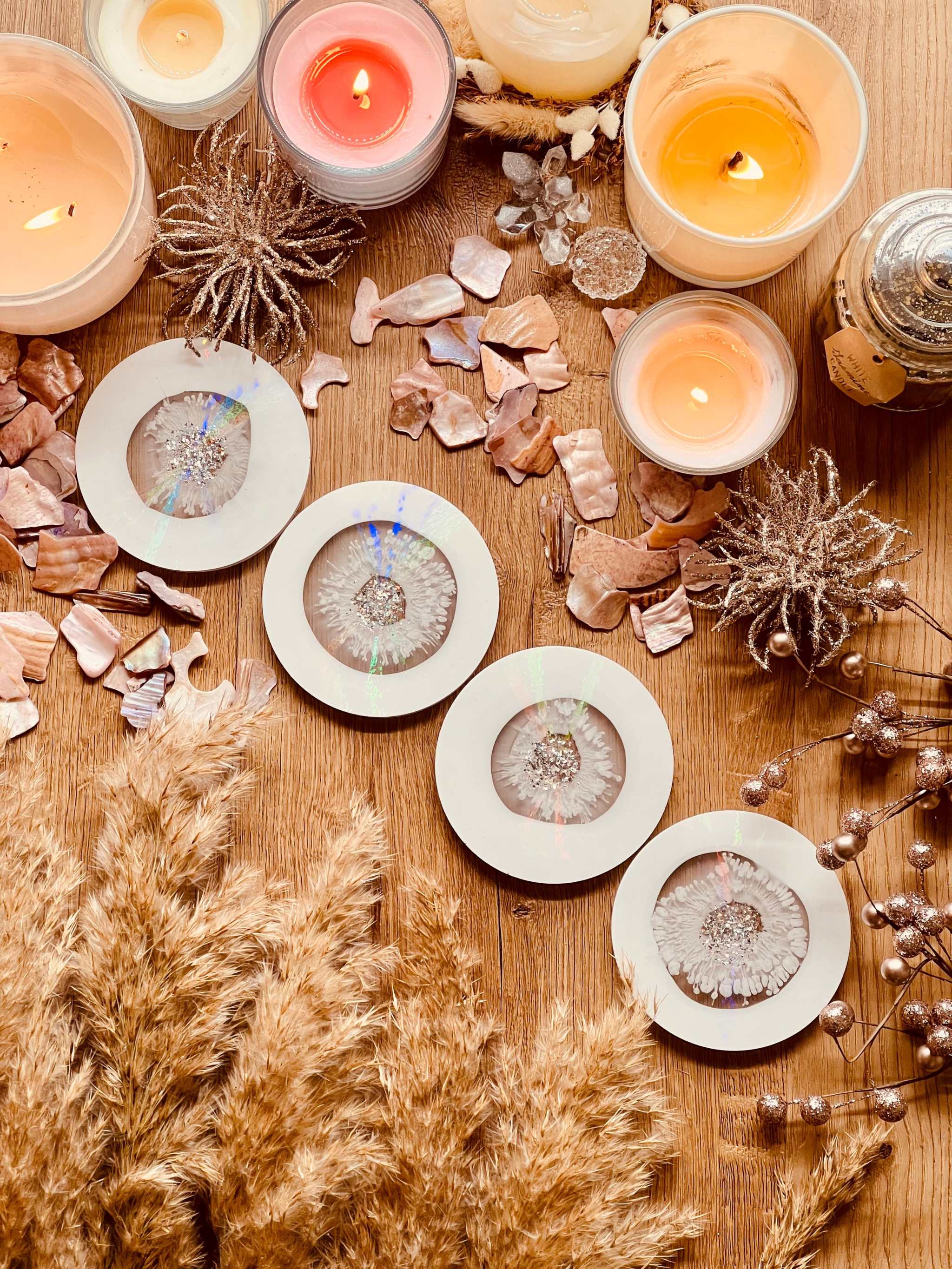 5 Untersetzer aus weißem Resin mit goldenen und holographischen Details handgemacht auf Holztisch mit Kerzen und Deko