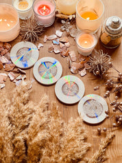 5 Untersetzer aus Resin in Weiss mit holographischem Design und silbernen Details auf Holztisch mit Kerzen und Dekoration